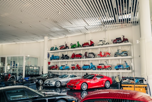 Collection of vintage scooters and modern cars displayed.