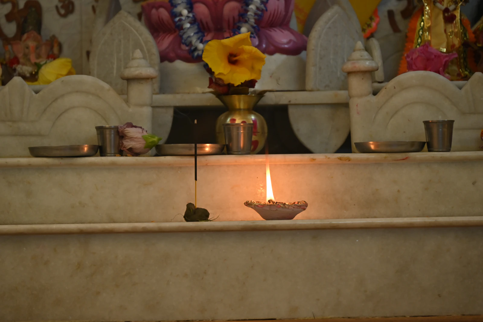 A lit diya with an incense stick and a flower