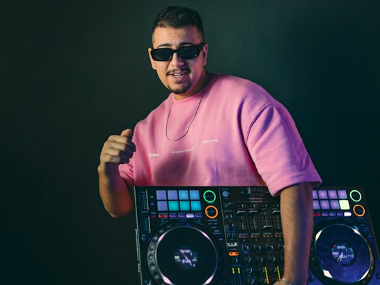 Dj in pink shirt with sunglasses and sunglasses and equipment