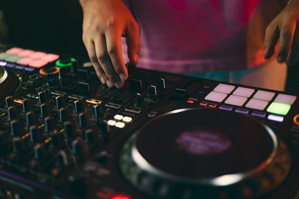 Hands mixing music on a console under club lights
