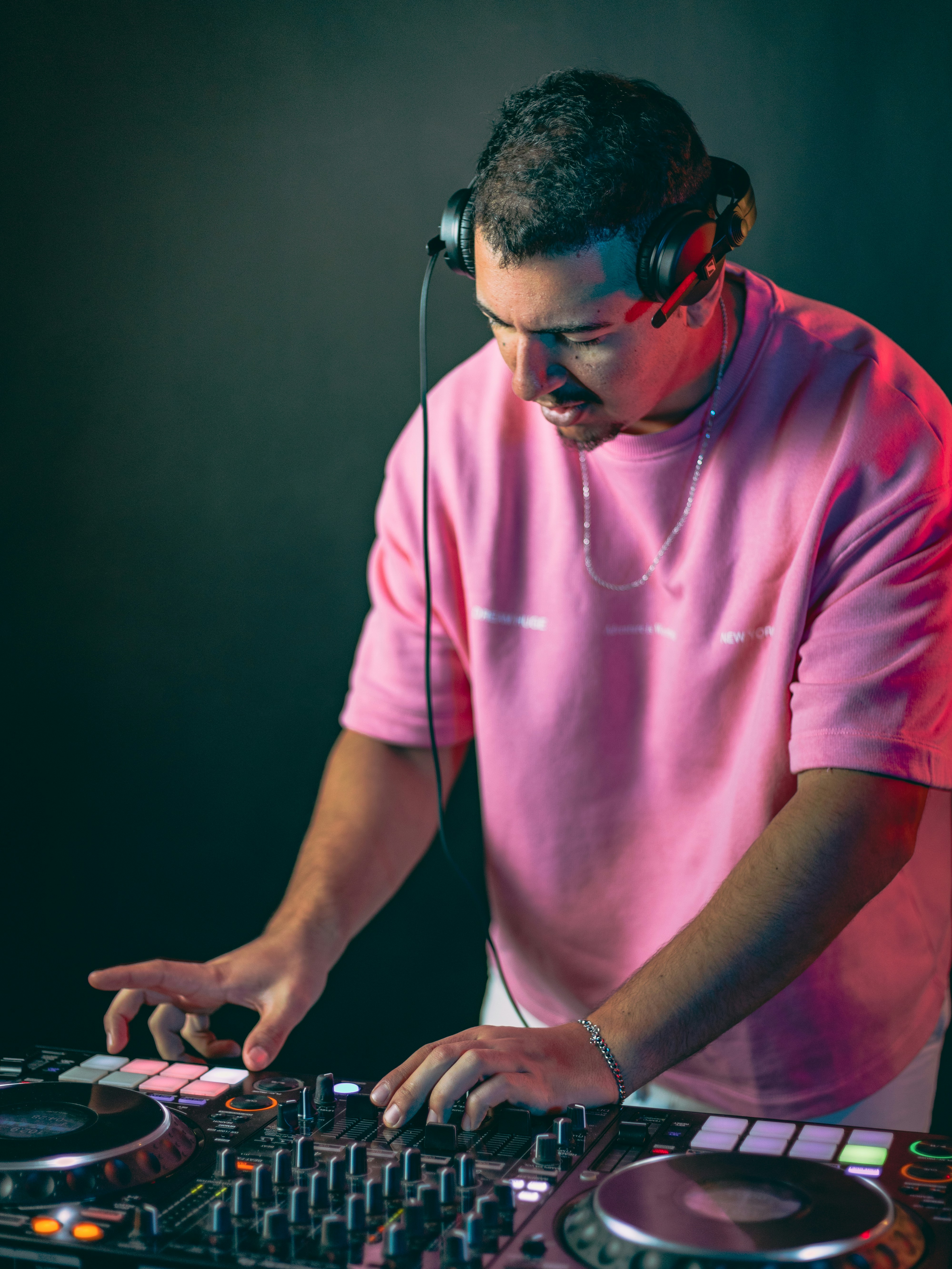 DJ im pinken Sweatshirt mischt Musik auf Plattenspielern