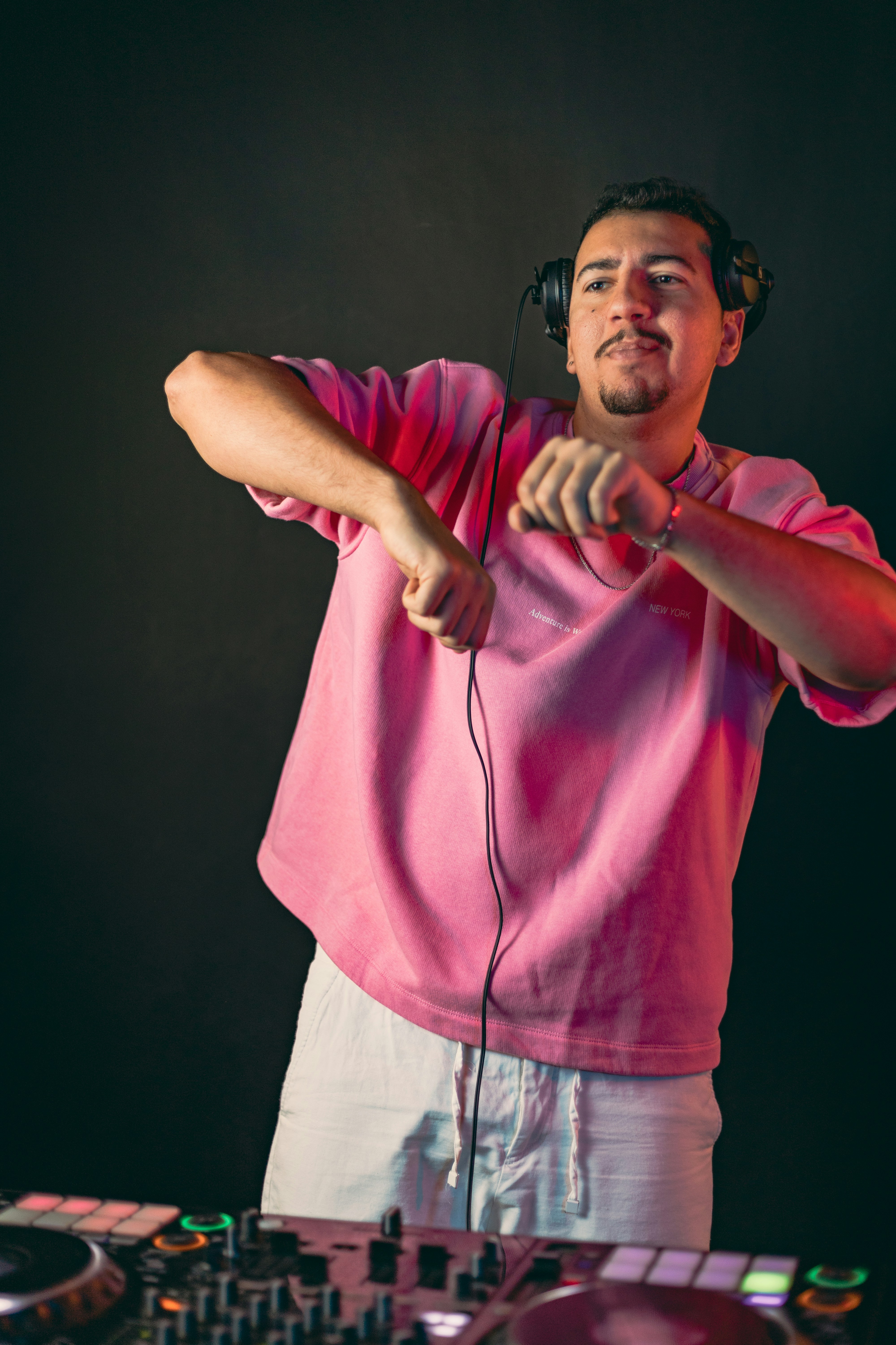 Un uomo con cuffie e una maglietta rosa fa il DJ.