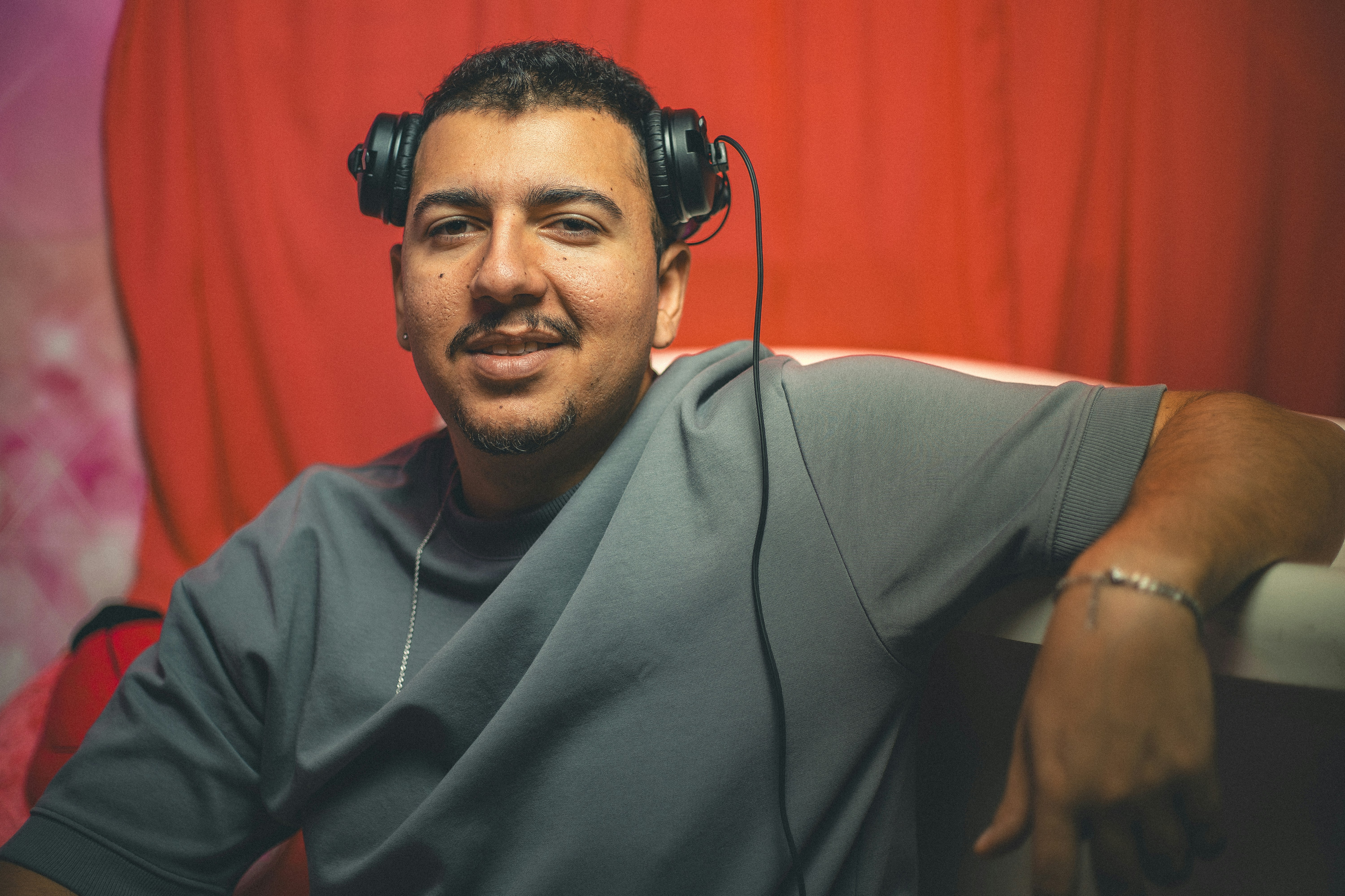 A man wearing headphones smiles at the camera.