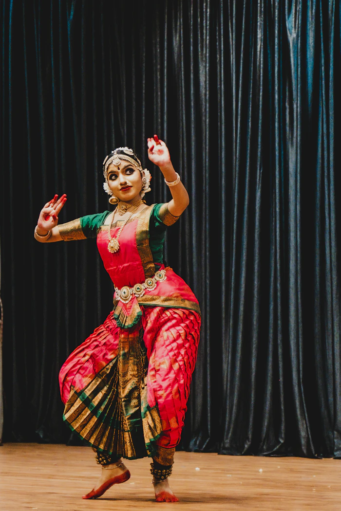 Bharatanatyam dancer in red and green costume performing on stage