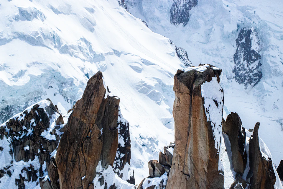 Snow-covered mountain range with rocky foreground, majestic peaks rising above the sky