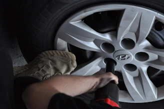 Mechanic using impact wrench on car wheel