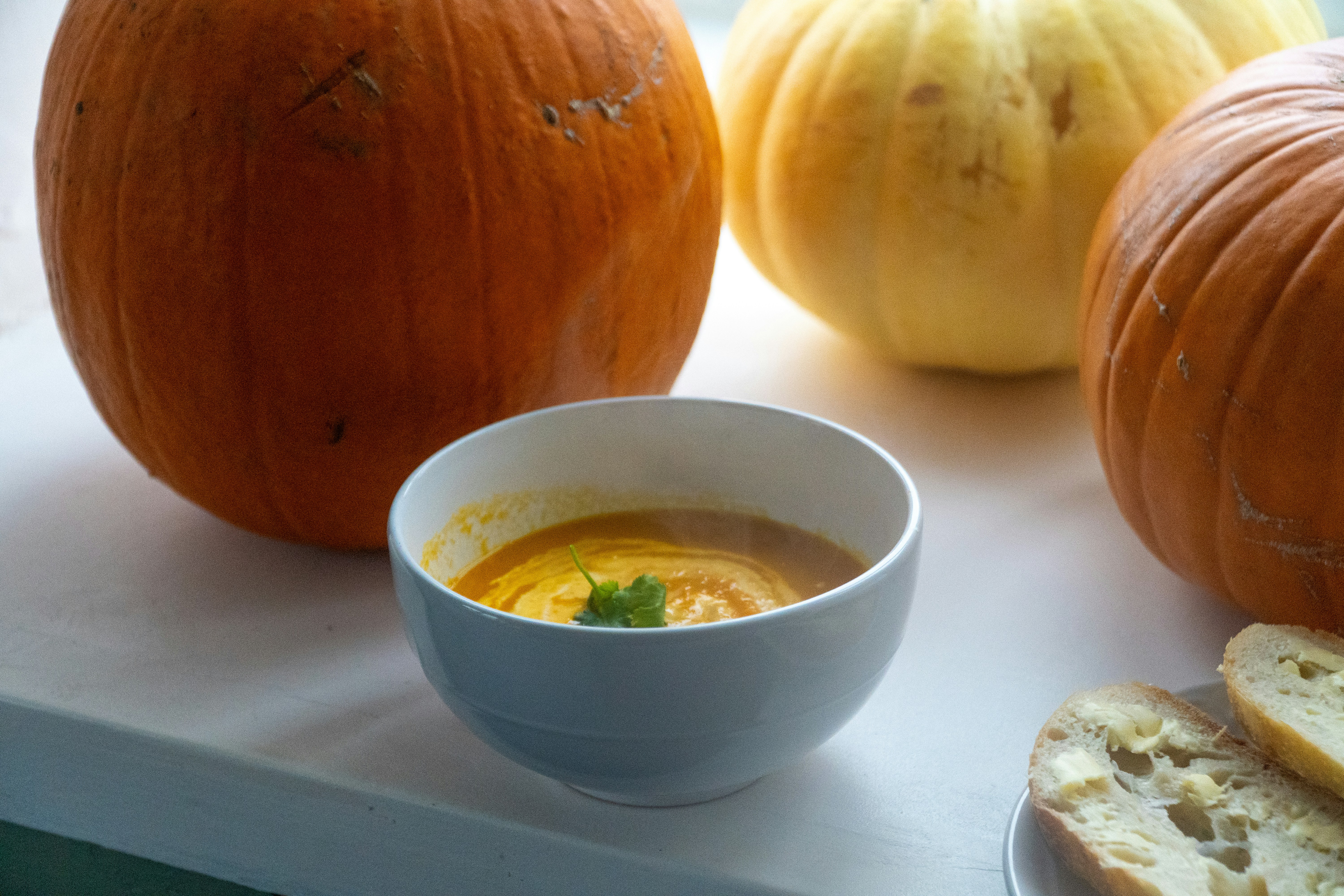 Bowl of pumpkin soup with bread and pumpkins
