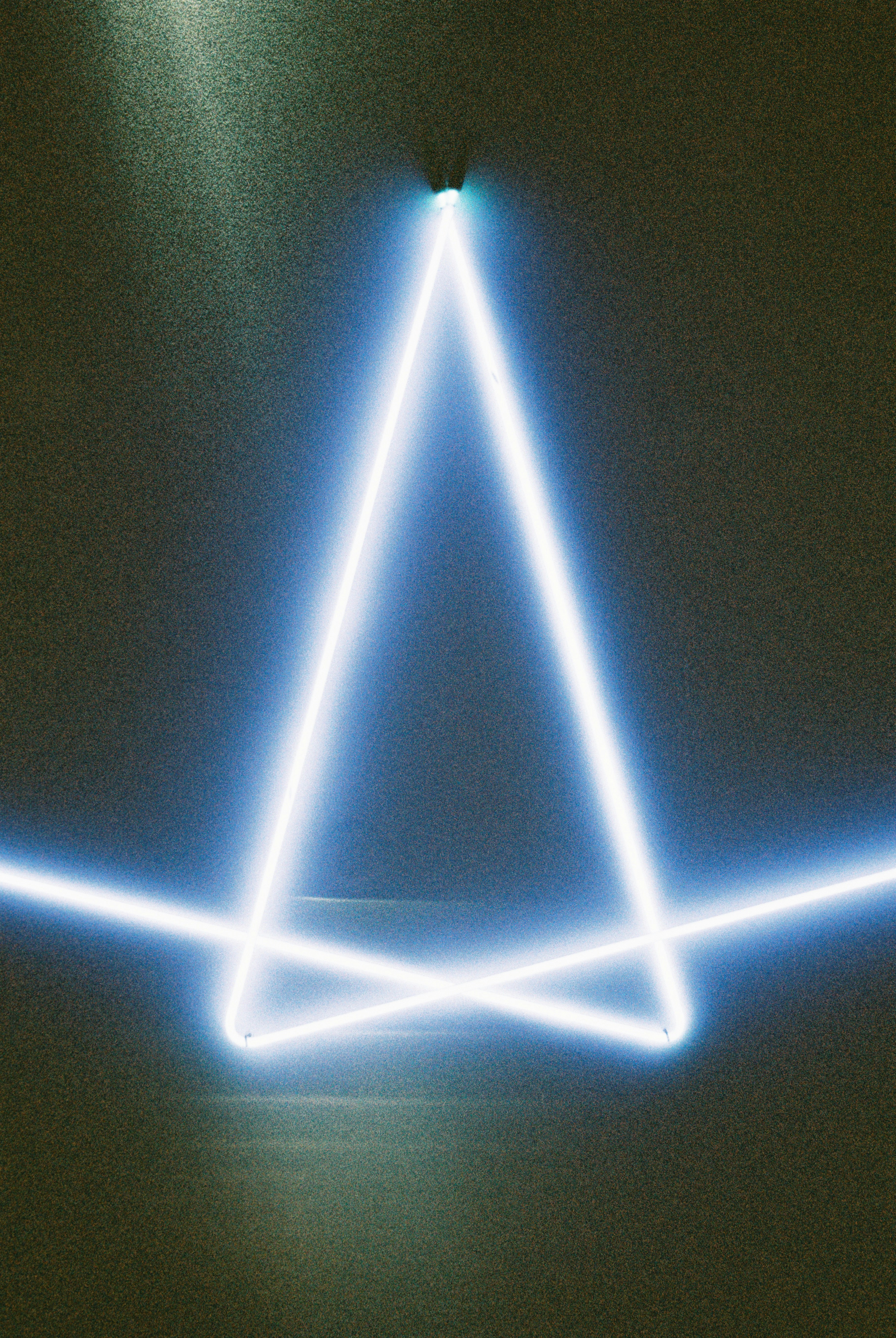 A glowing blue triangle on a dark background.