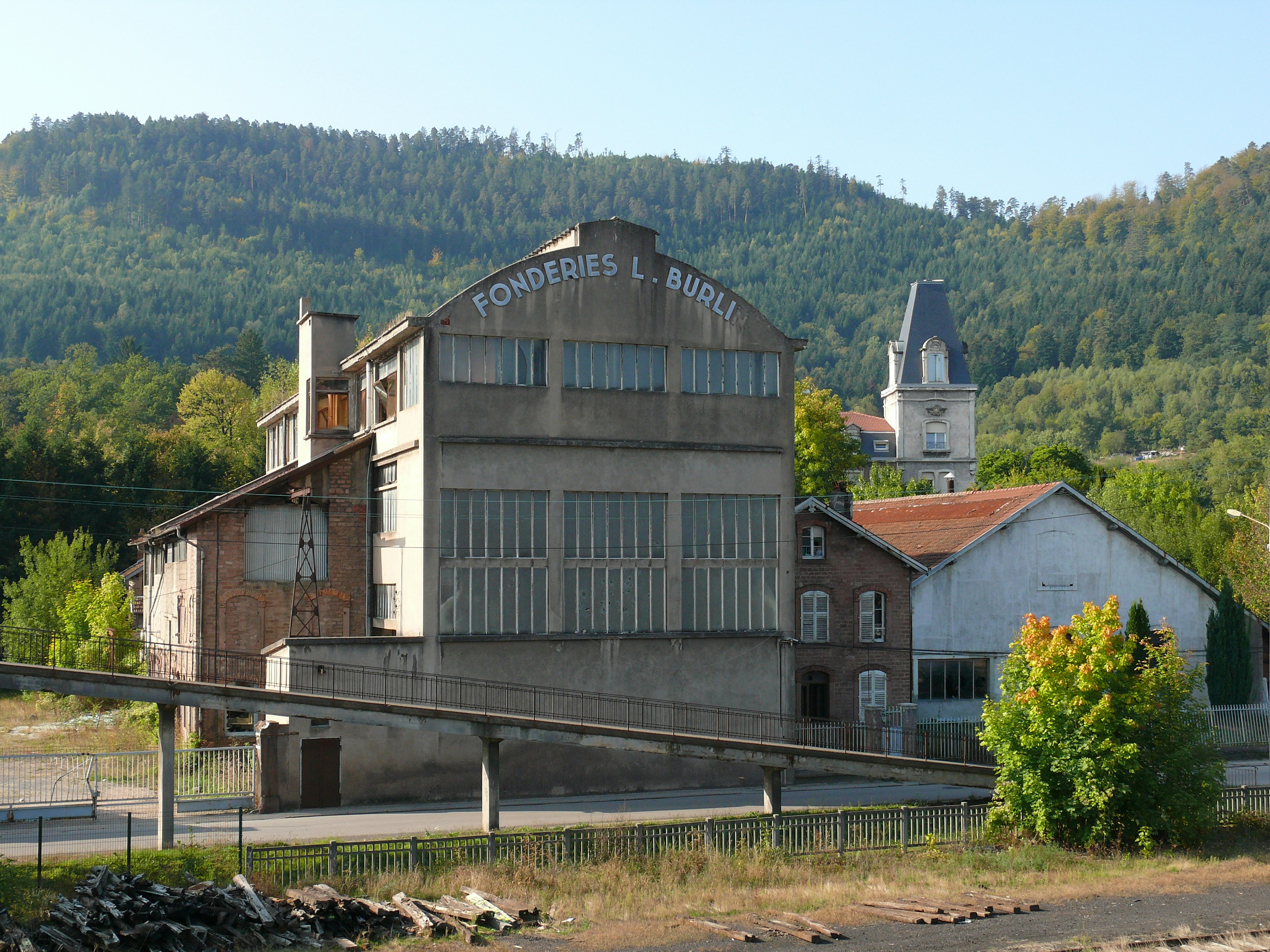 Old industrial building with a church steeple behind.