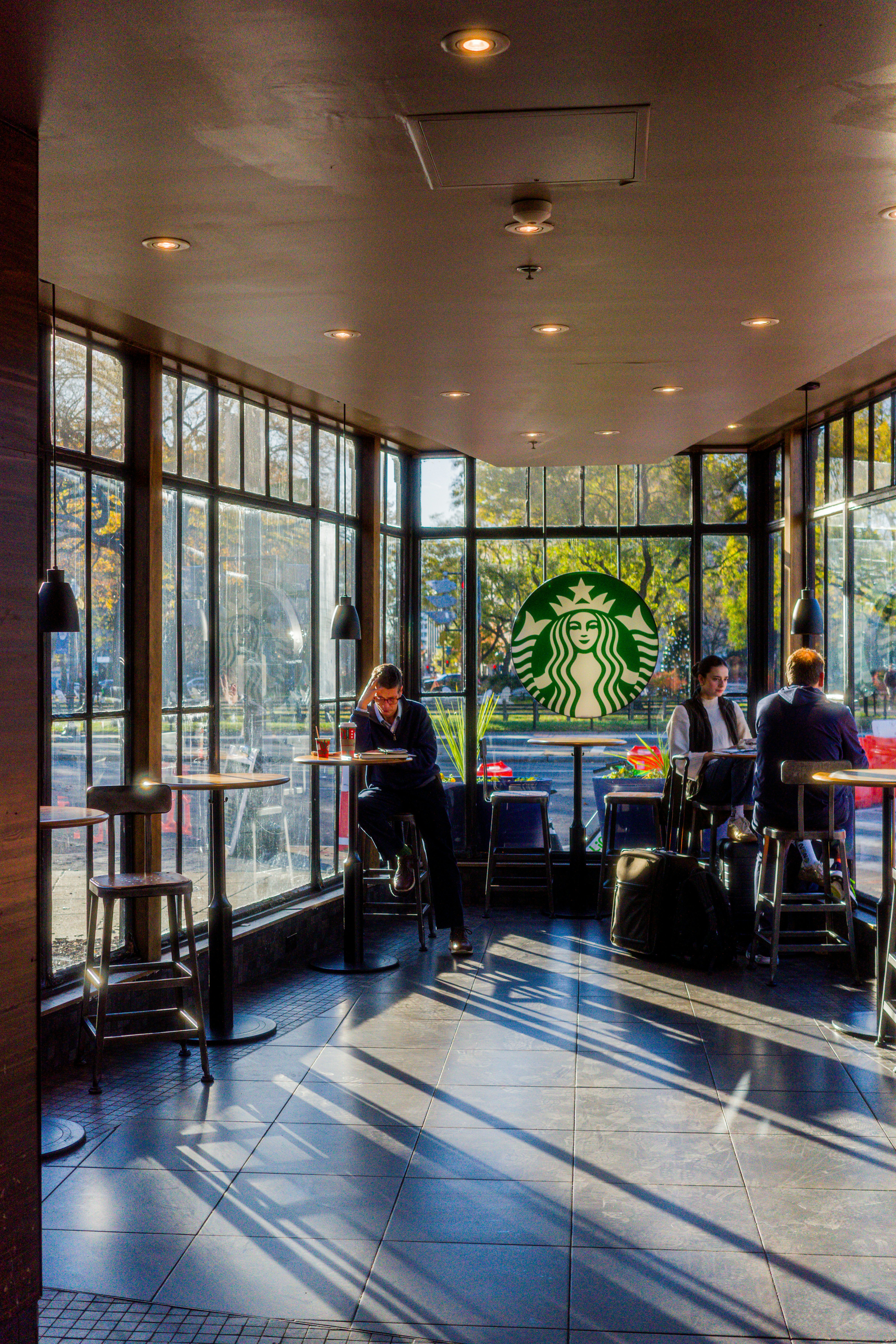 People sitting inside a starbucks cafe by the window.