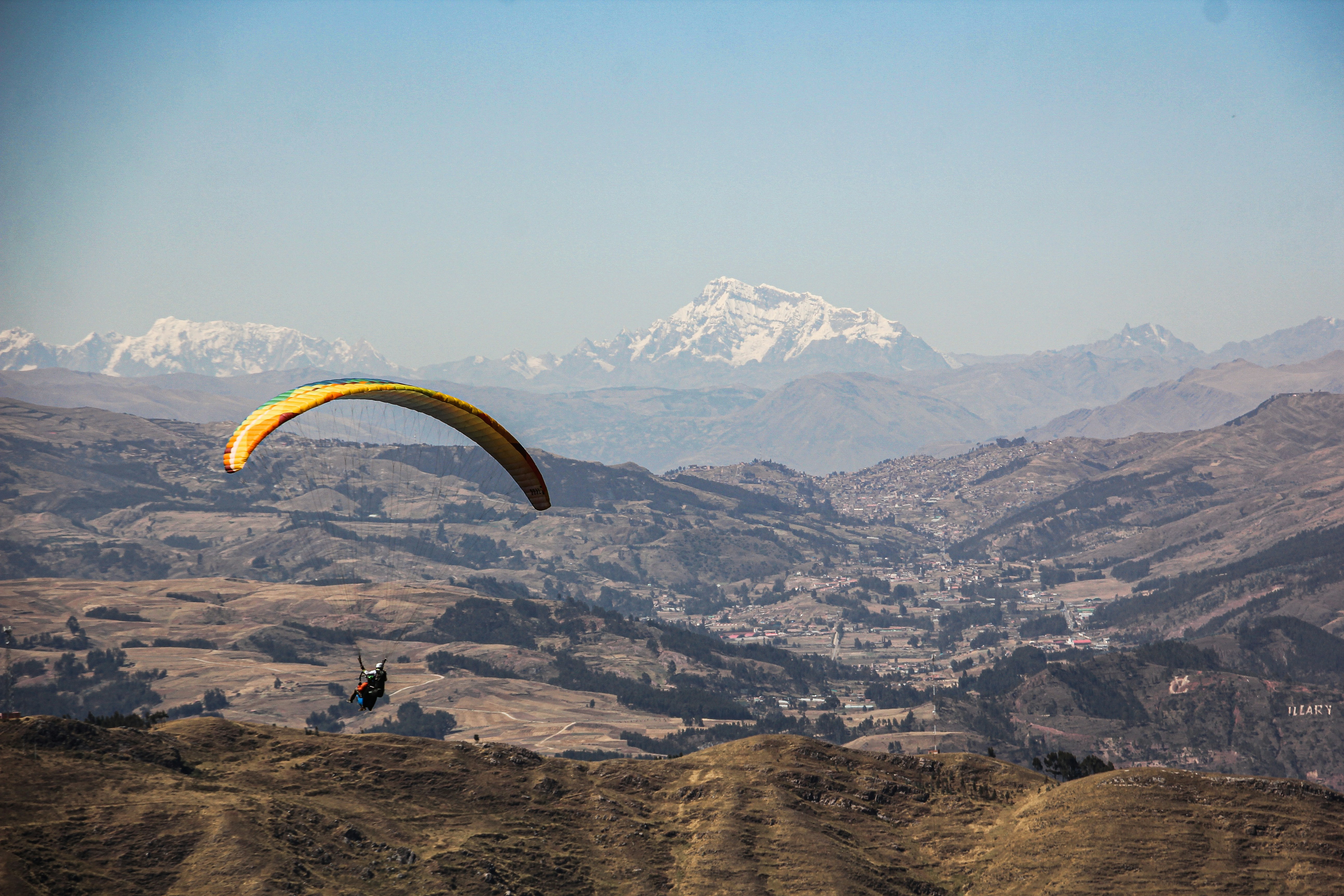 Paraglider flying over a mountainous landscape