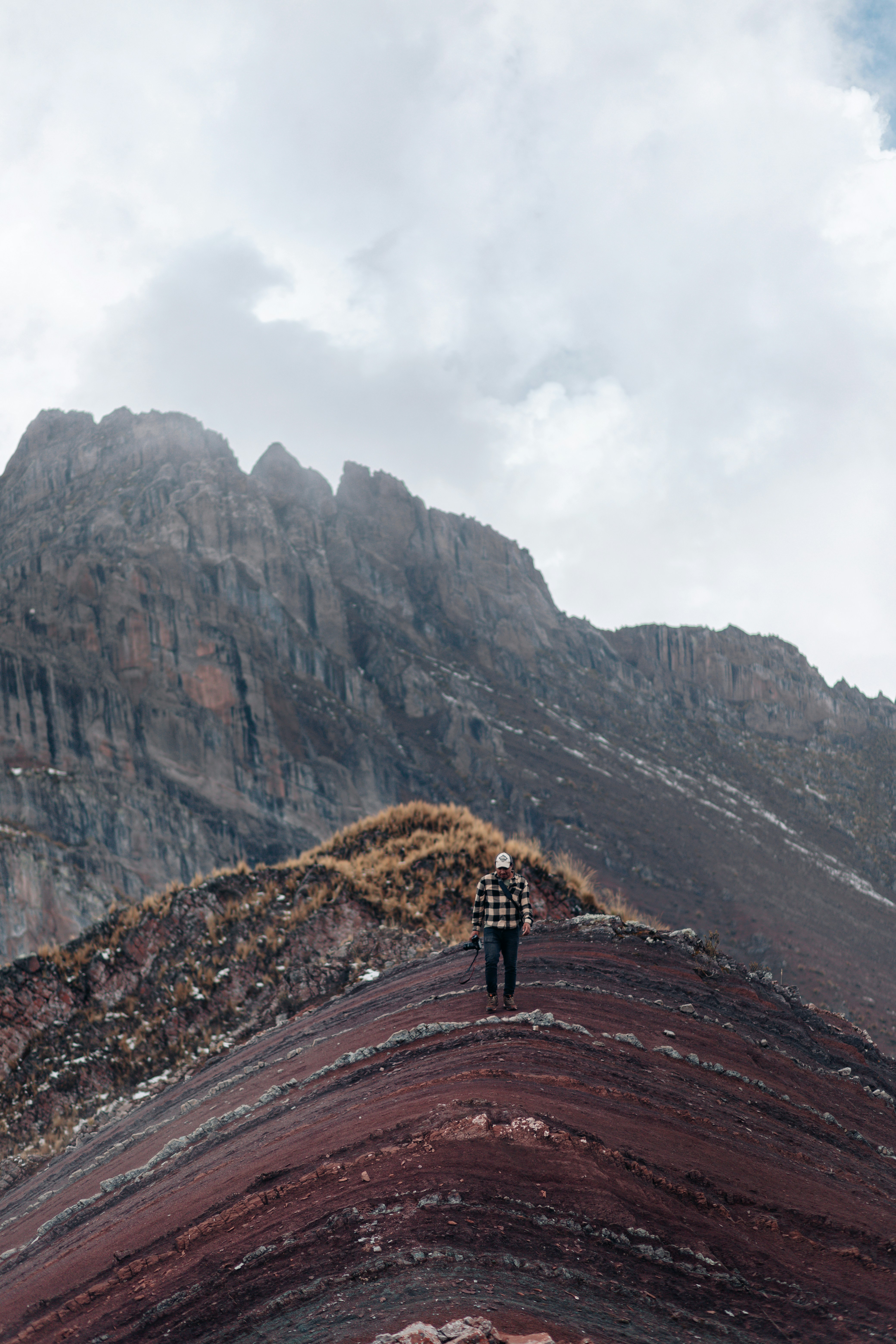 A person walks on a colorful mountain ridge
