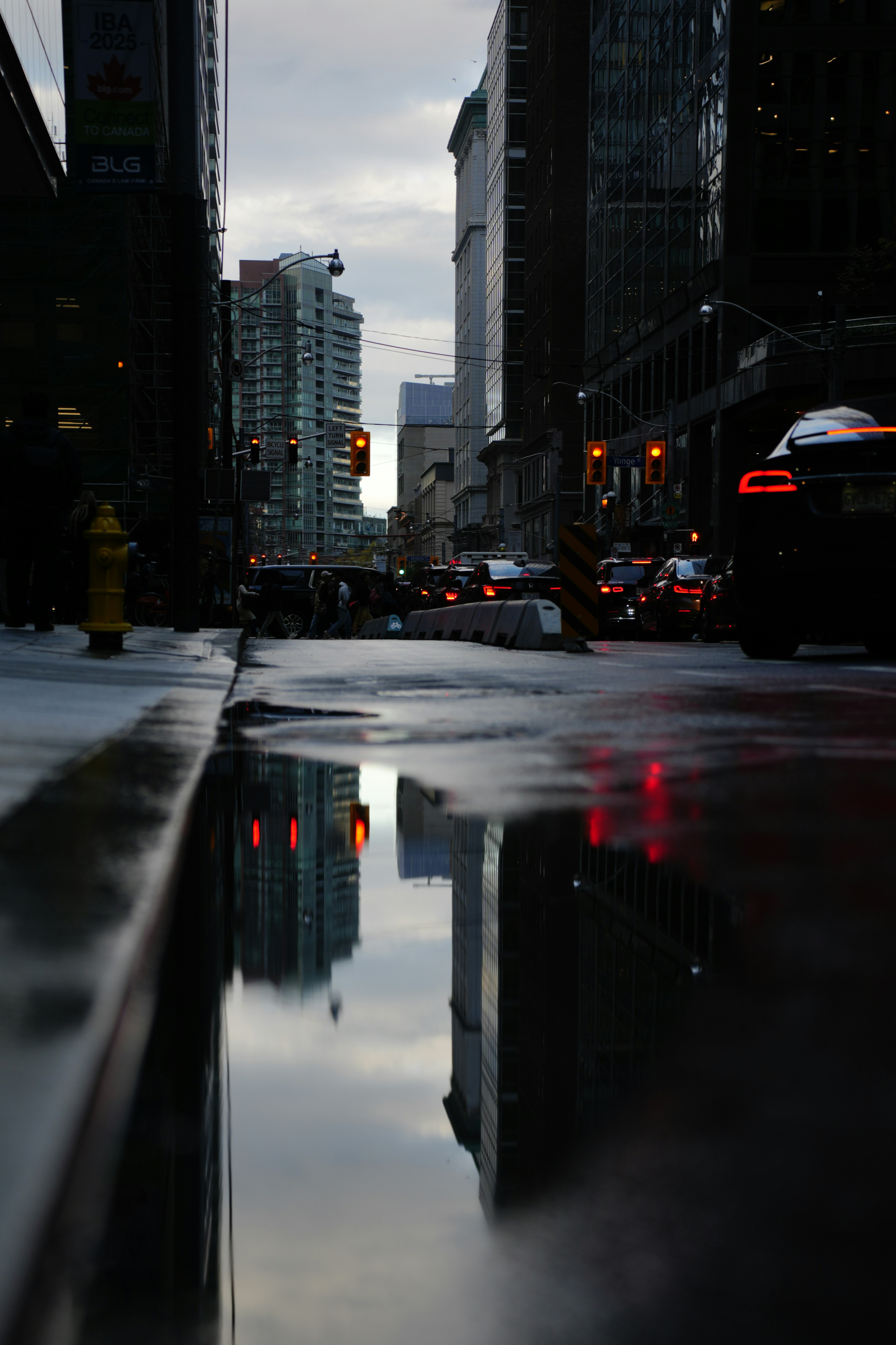 Wet city street reflecting buildings and traffic lights at dusk