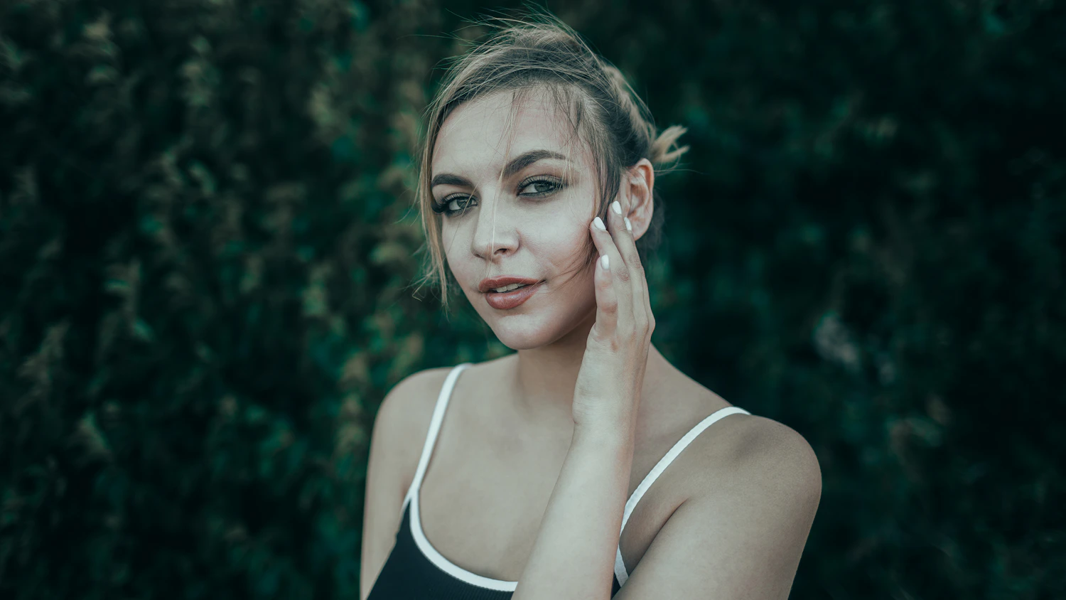 Close-up portrait of a woman with her hand resting near her jaw and cheek before TMJ botulinum toxin consultation