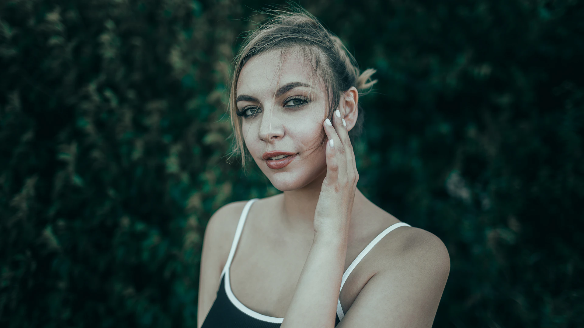 Young woman with hand on cheek looking at camera