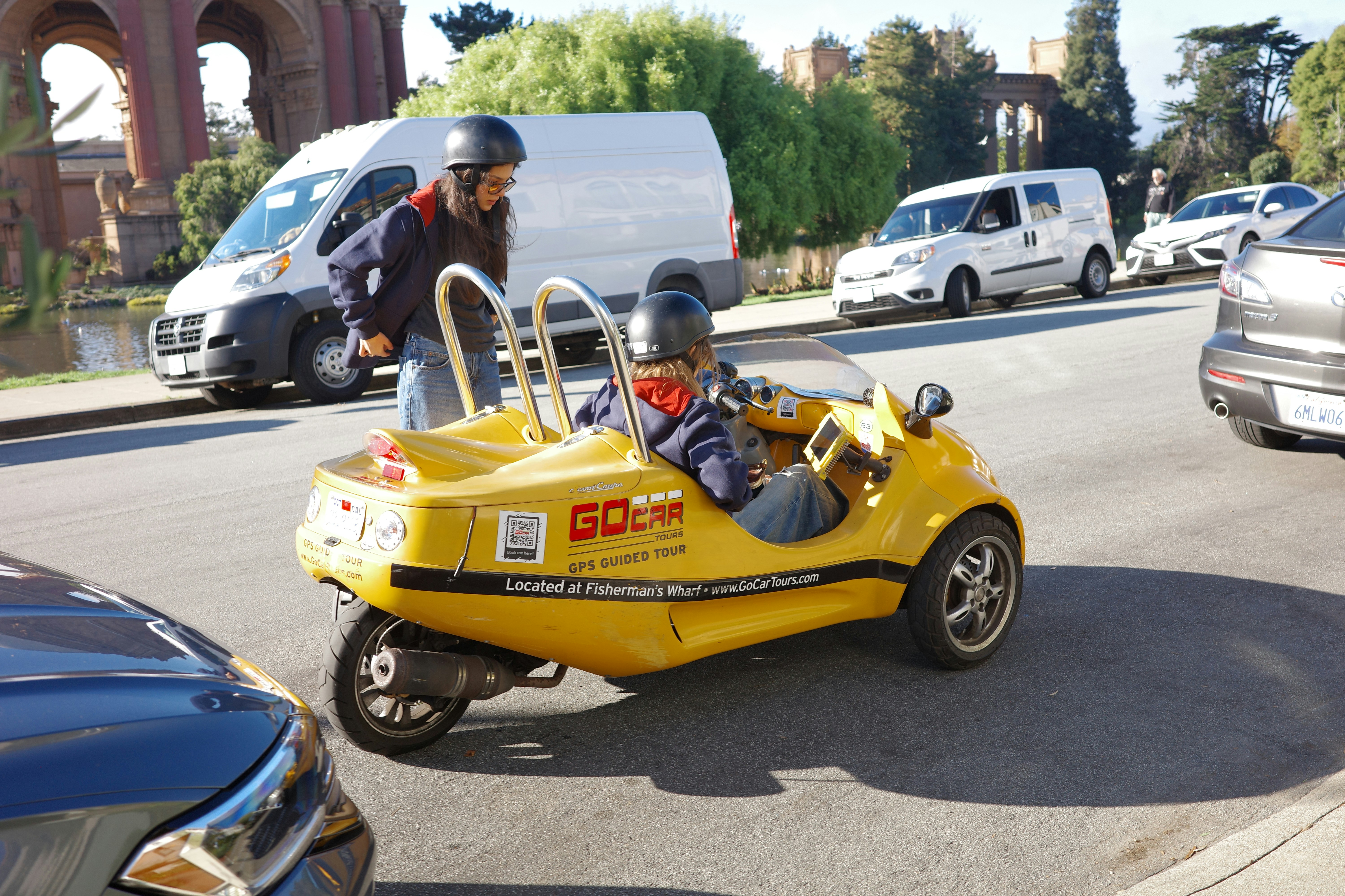 Two people in a yellow three-wheeled car