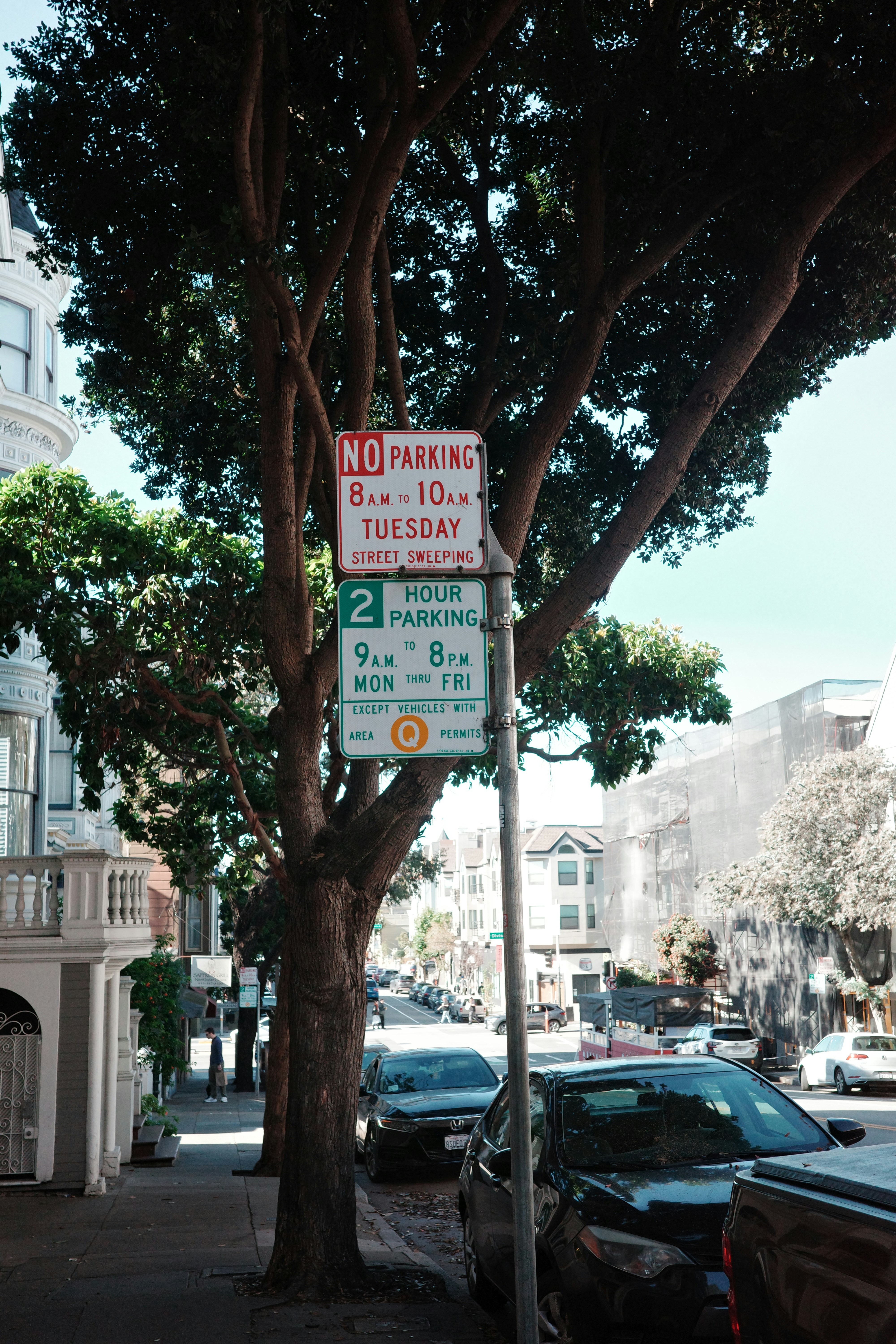 Panneaux de rue sur un arbre avec des voitures garées