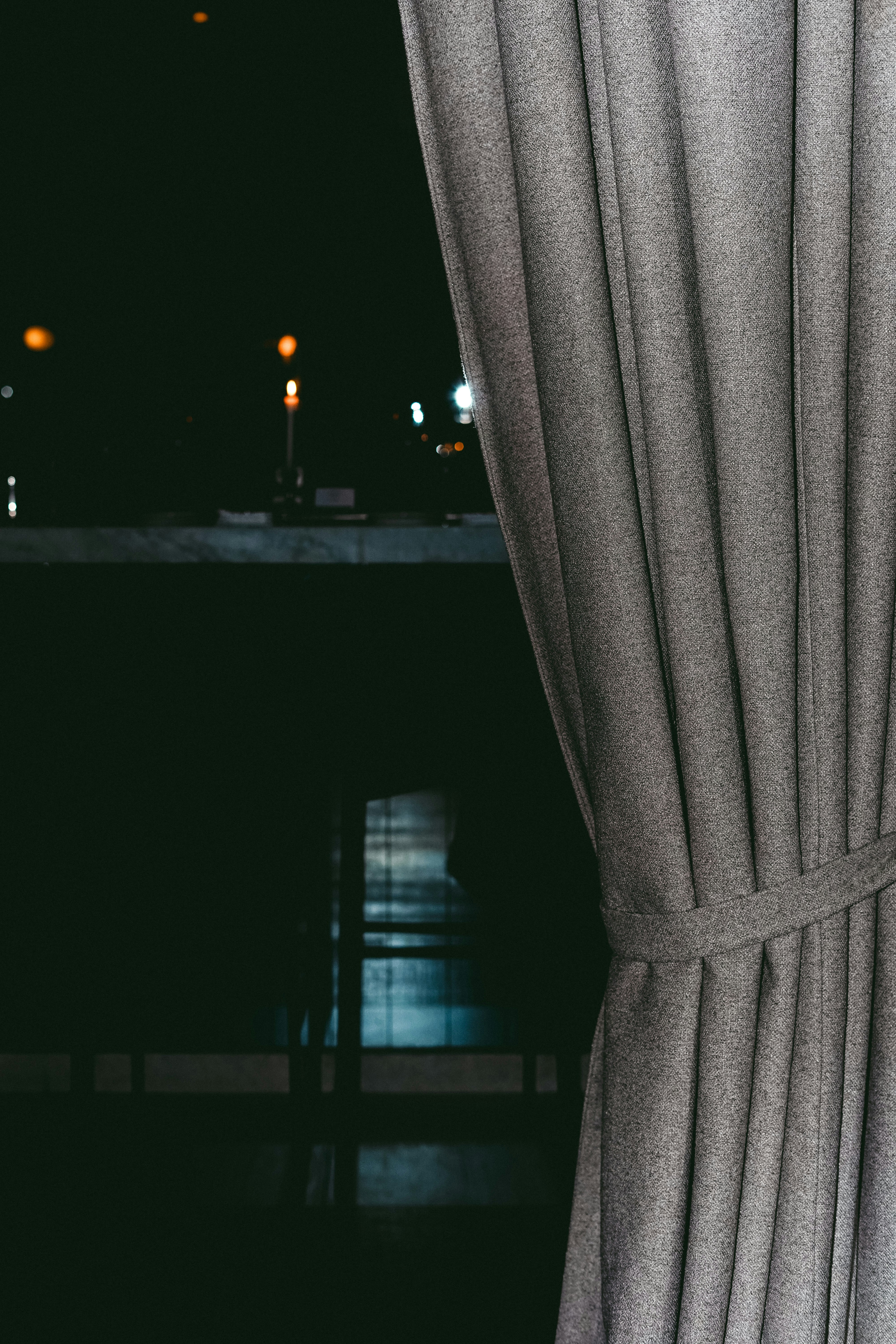Gray curtain partially covering a dark room with lights.
