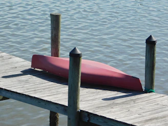 Red canoe resting on a wooden dock.