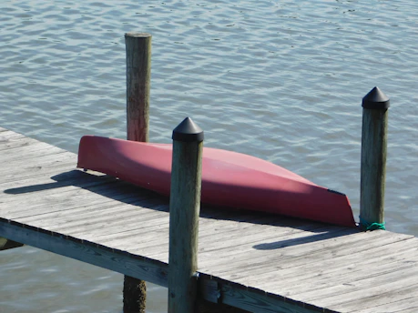 Red canoe resting on a wooden dock.