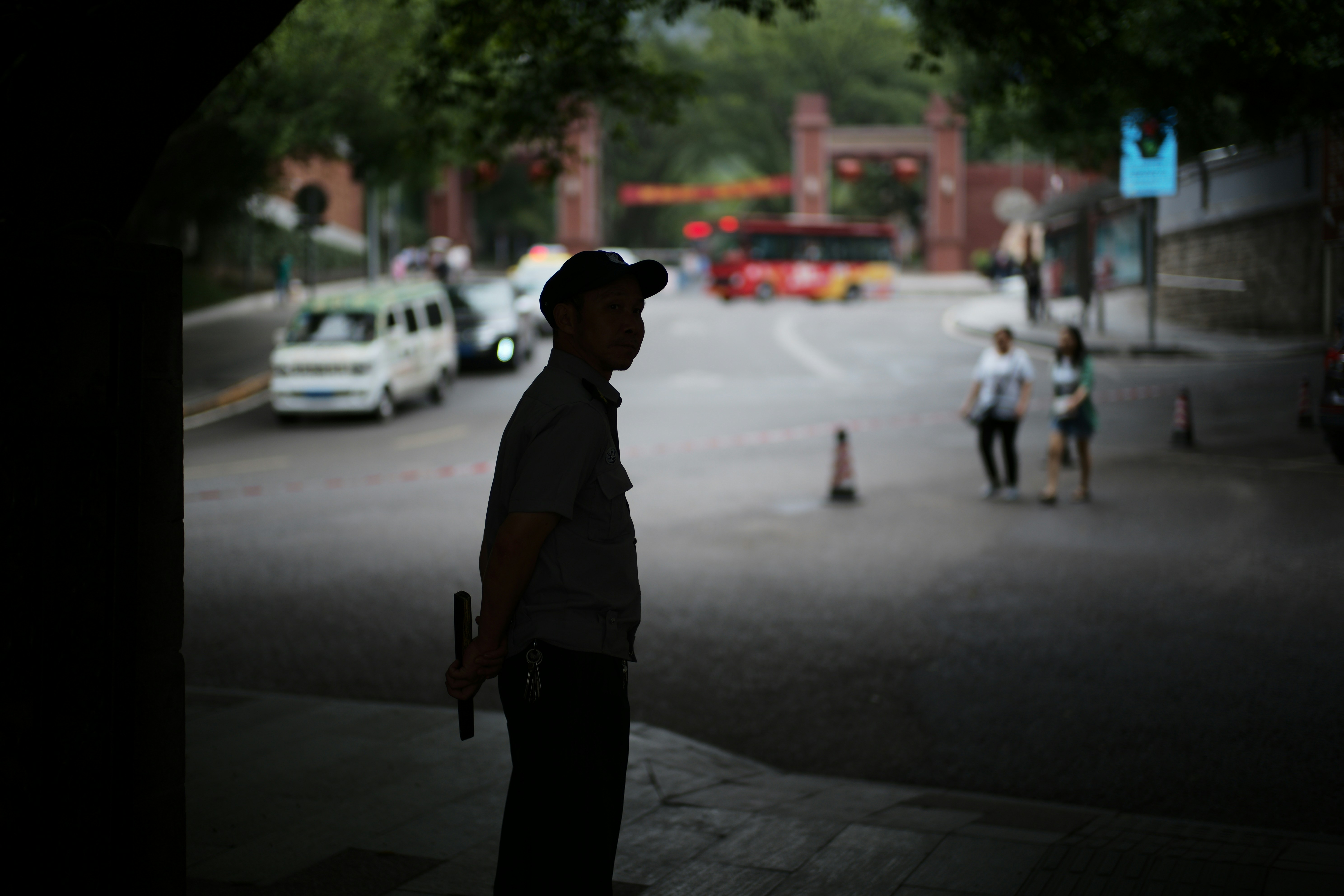 Man in uniform stands by street with traffic.