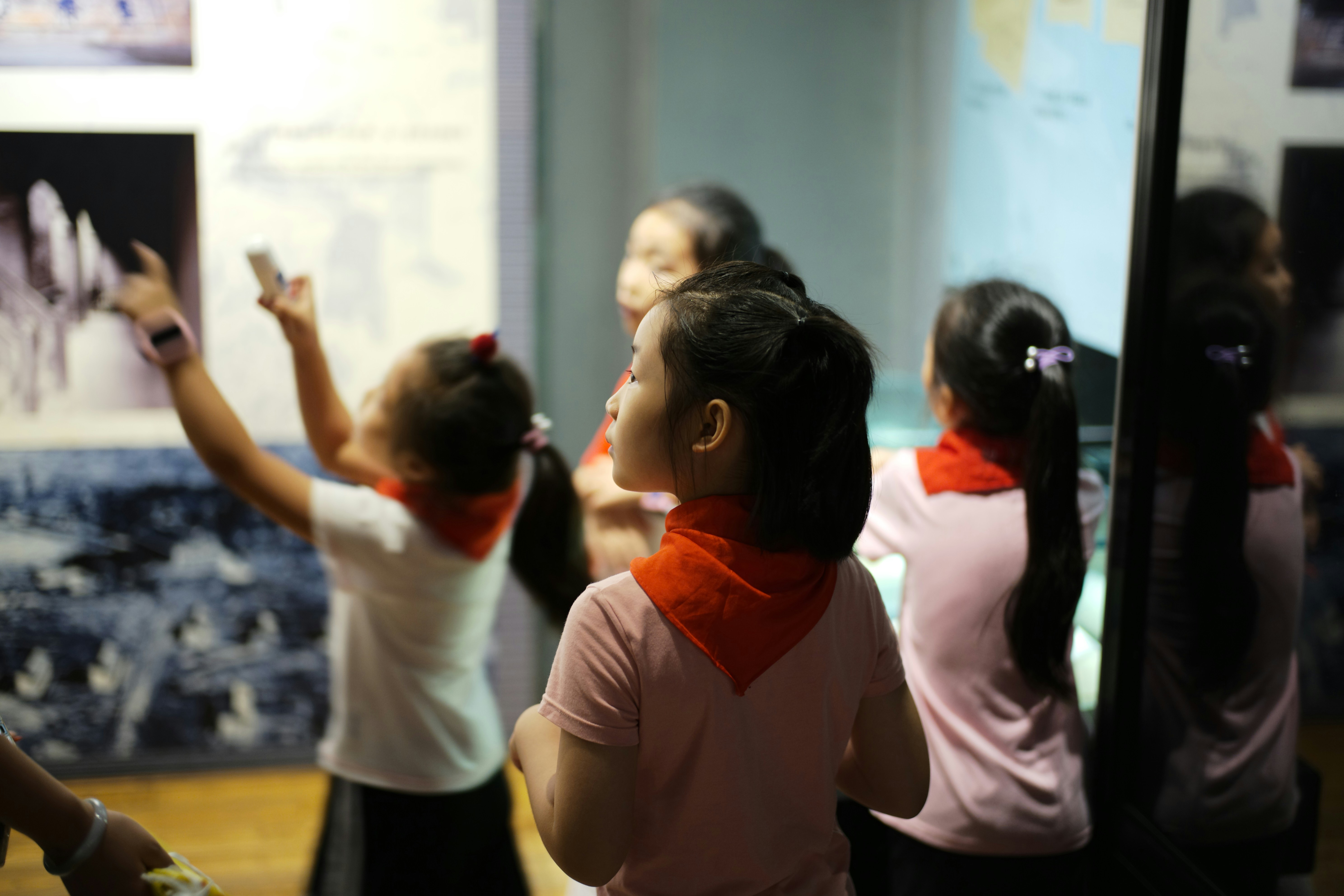 Children in red scarves looking at exhibits