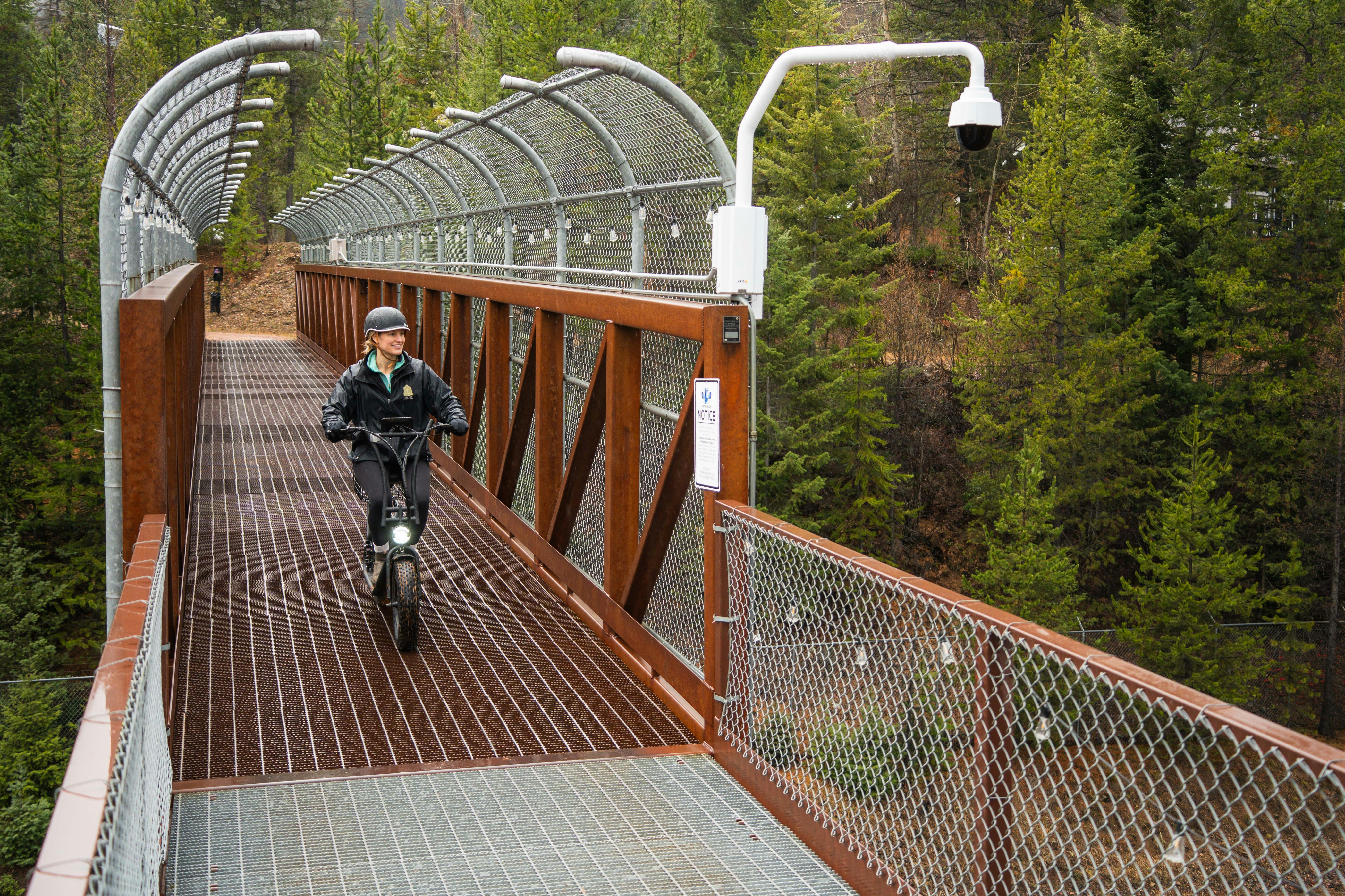 Person riding an electric scooter on a modern elevated walkway.