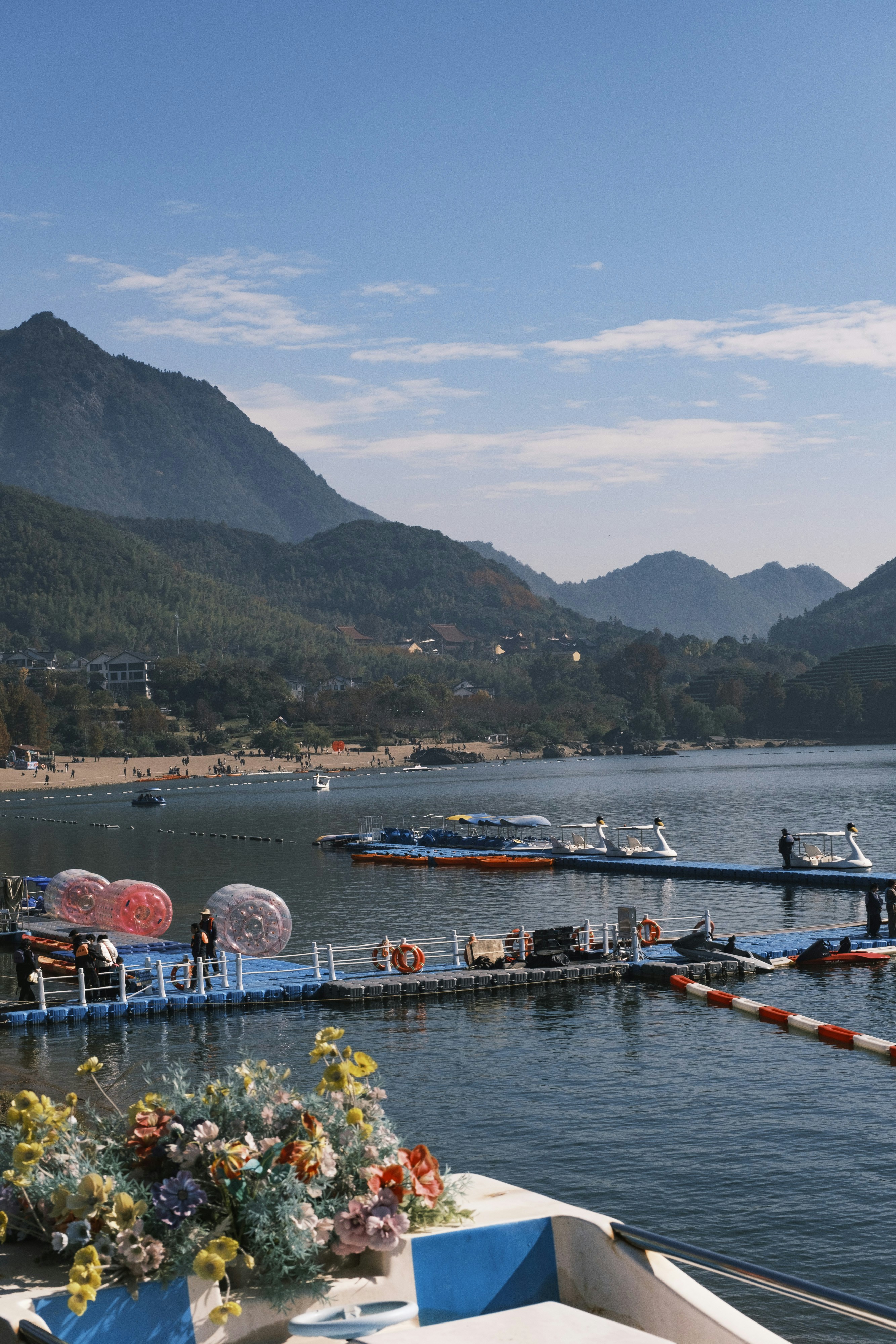 Boats docked on a calm lake with mountains in background.