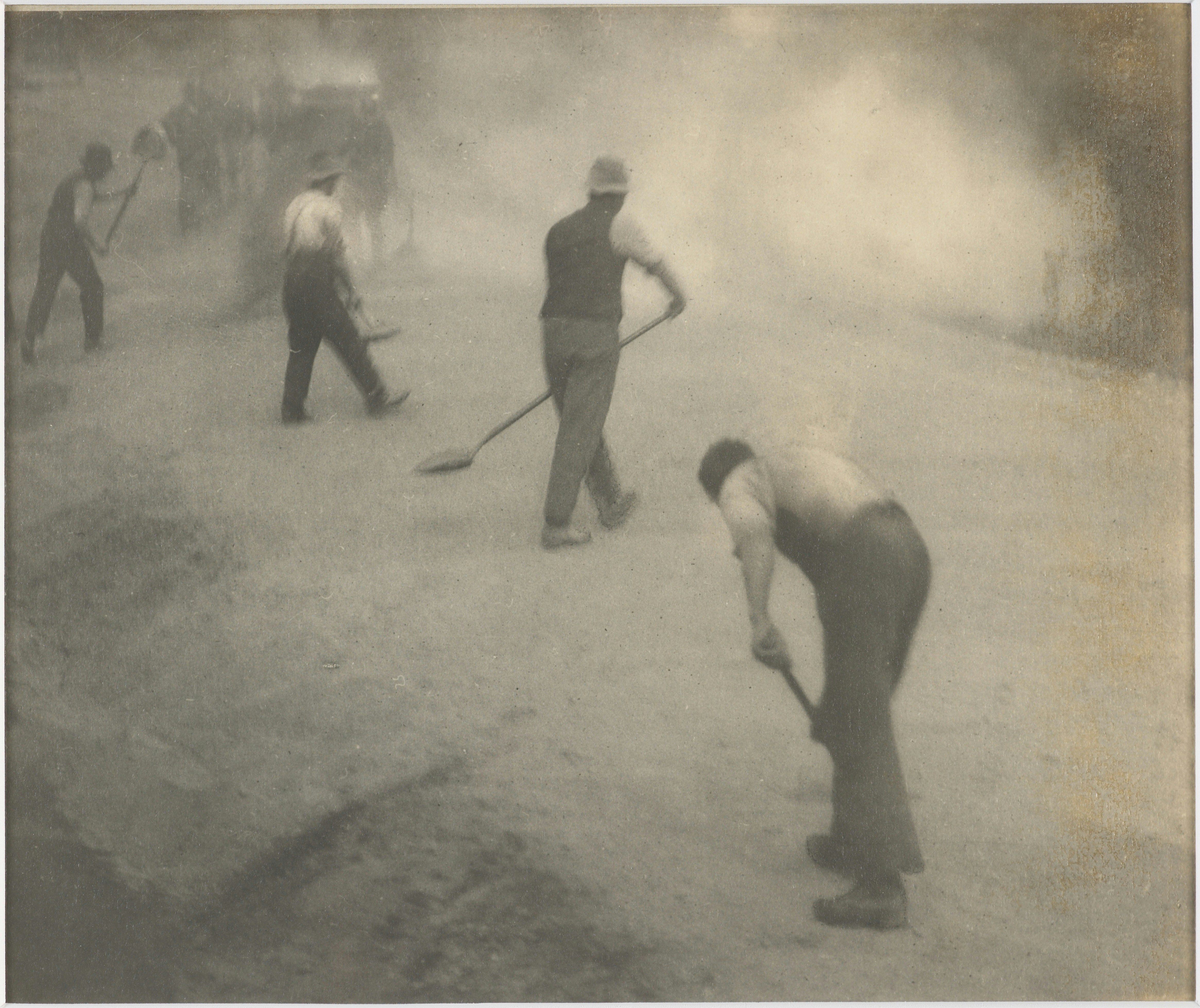 Men working on a dusty road with shovels