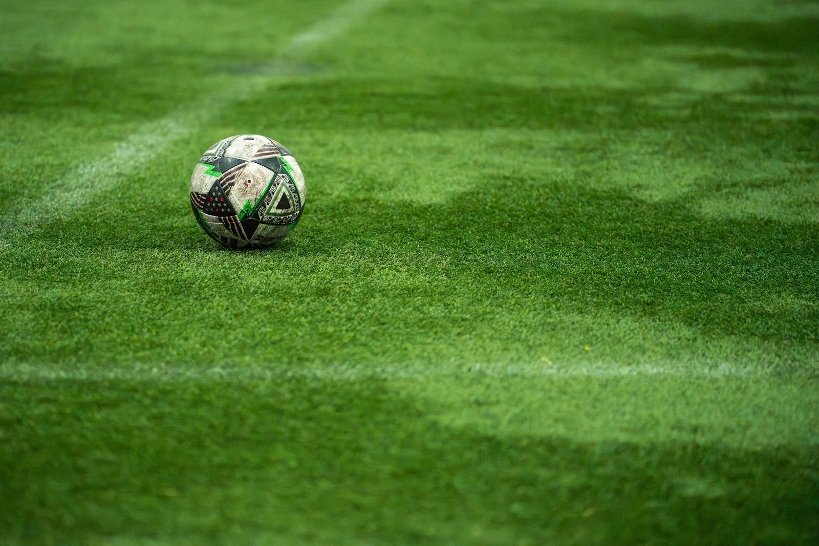 A football resting on the green turf of a football pitch