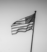 An american flag waves against a clear sky.