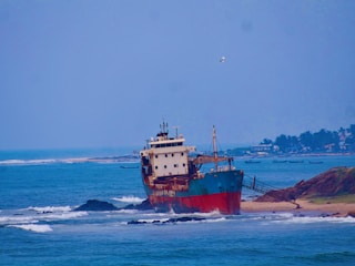 Shipwrecked vessel grounded on a sandy shore.