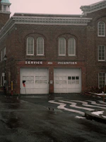 Old brick fire station with two garage doors.