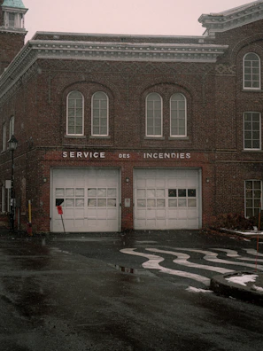 Old brick fire station with two garage doors.