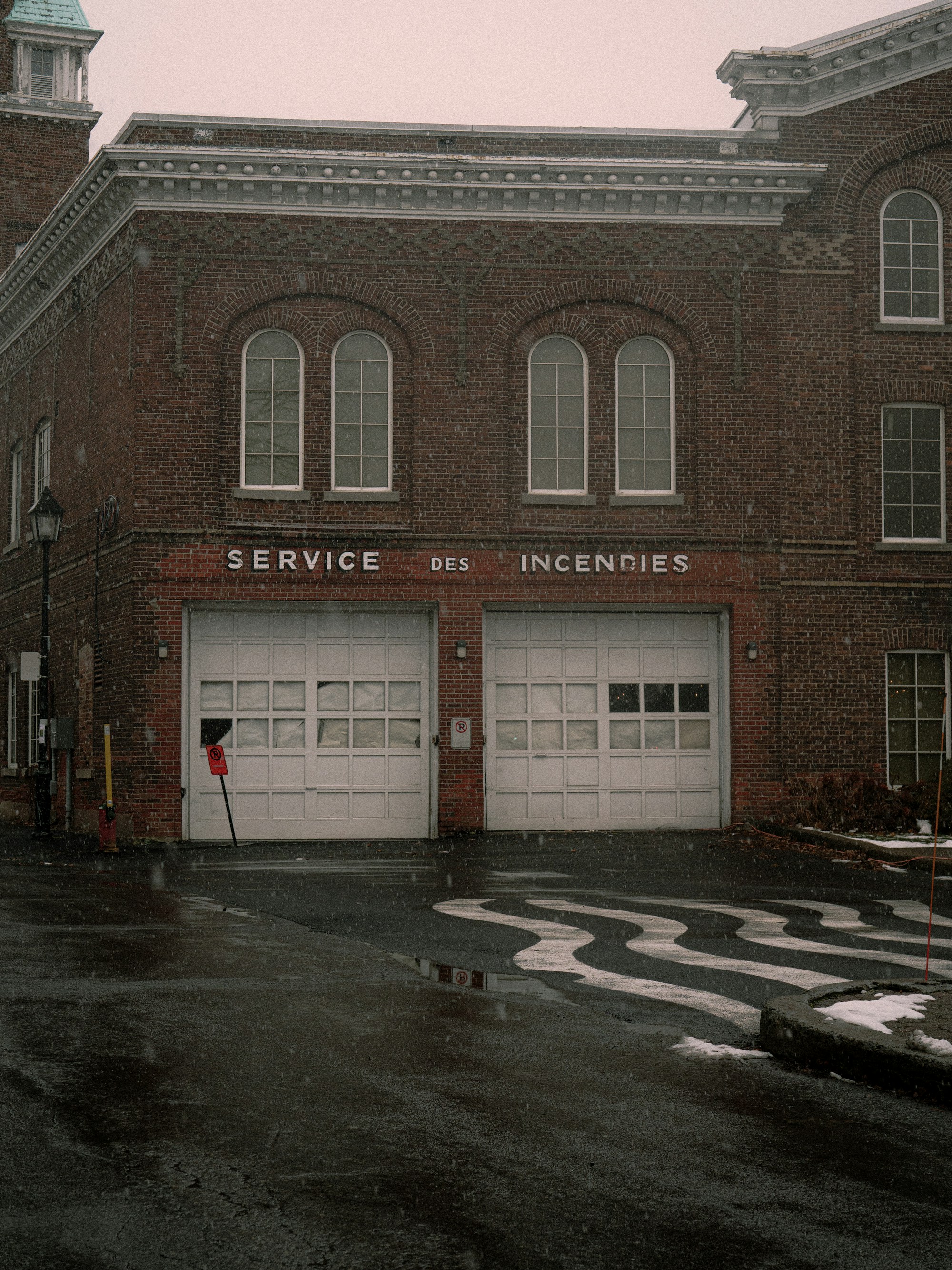 Old brick fire station building with garage doors, the kind of structure being converted into homes