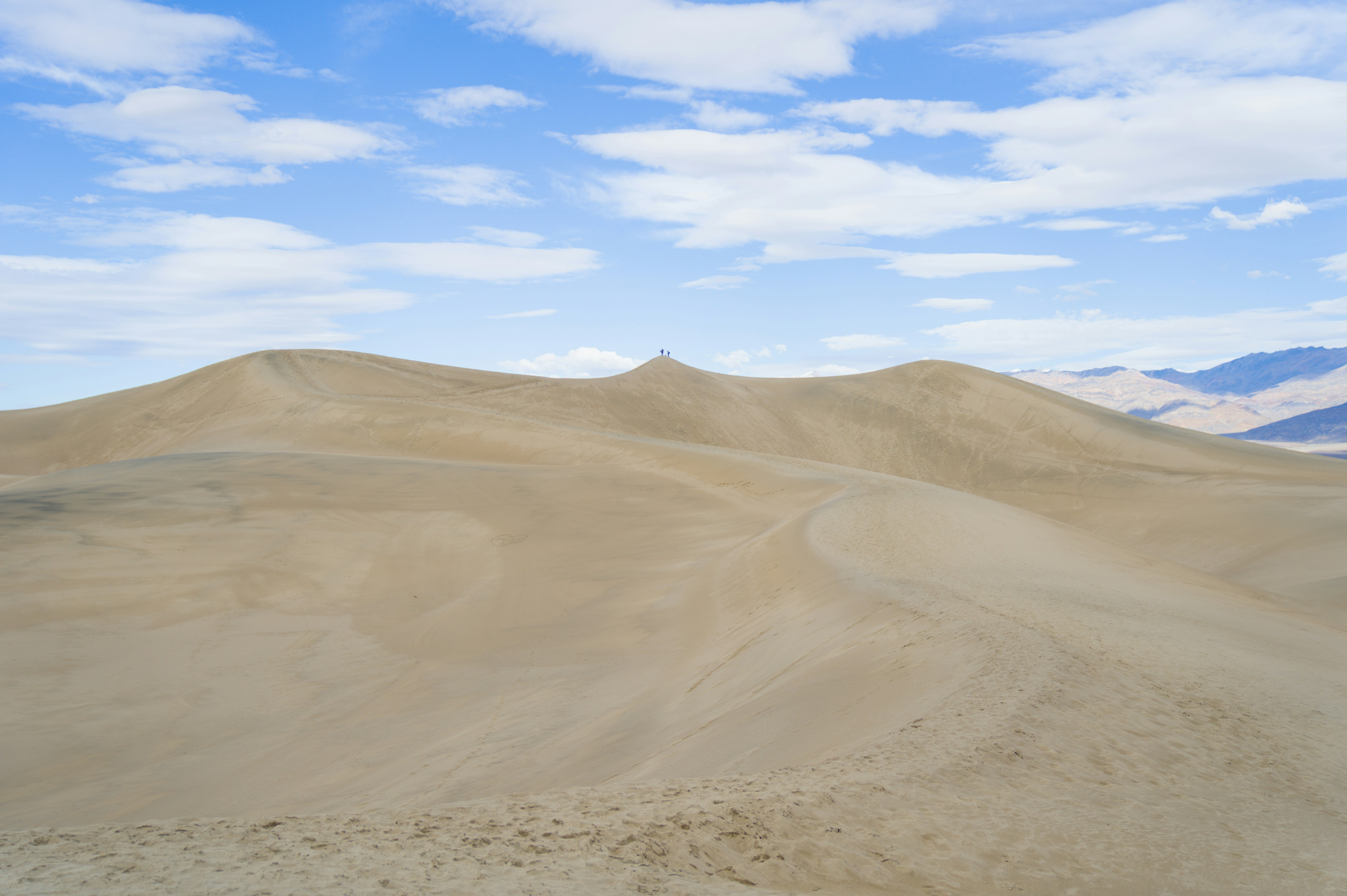 Vast sand dunes under a cloudy blue sky
