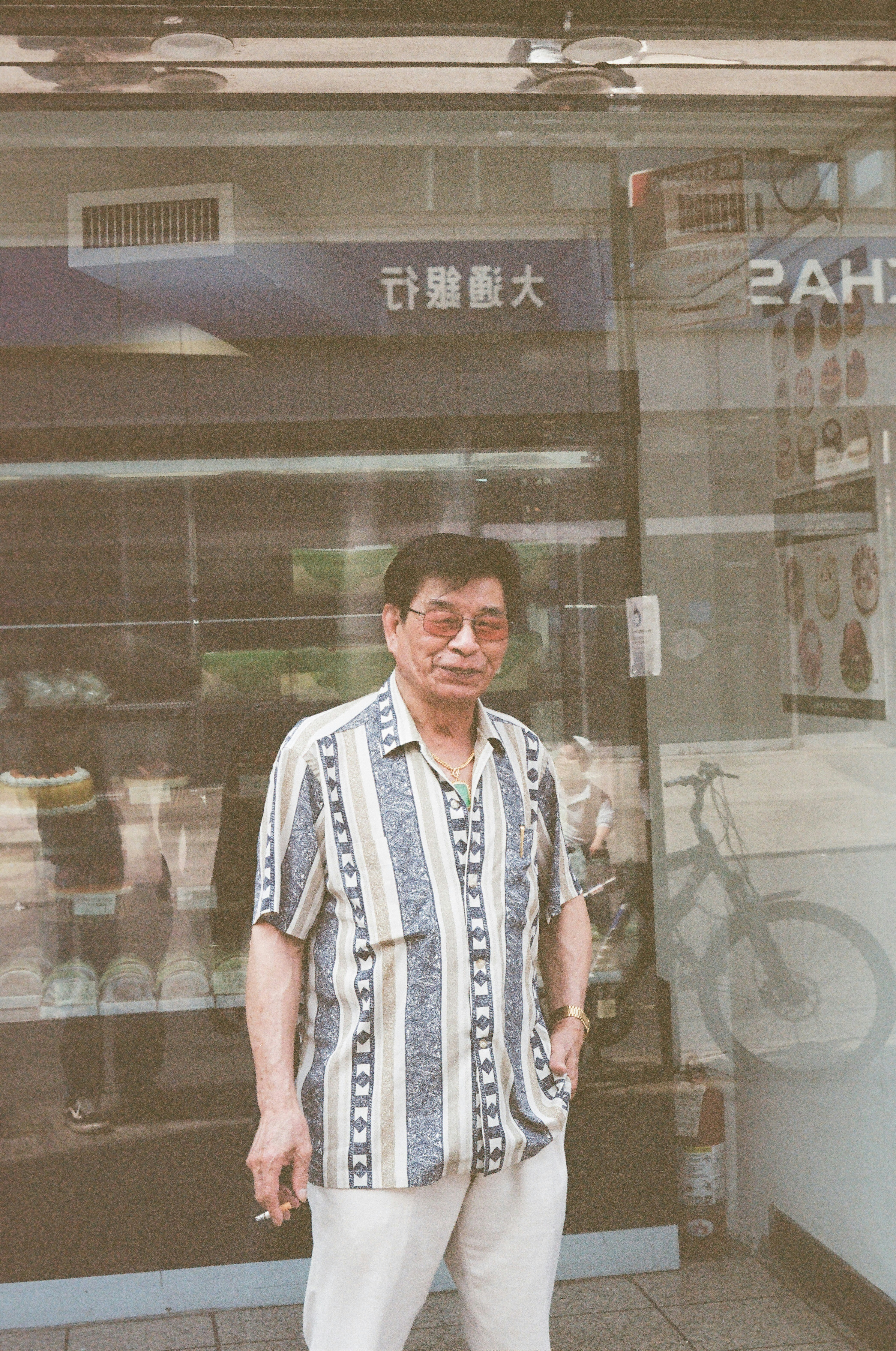 Elderly man in striped shirt stands outside store