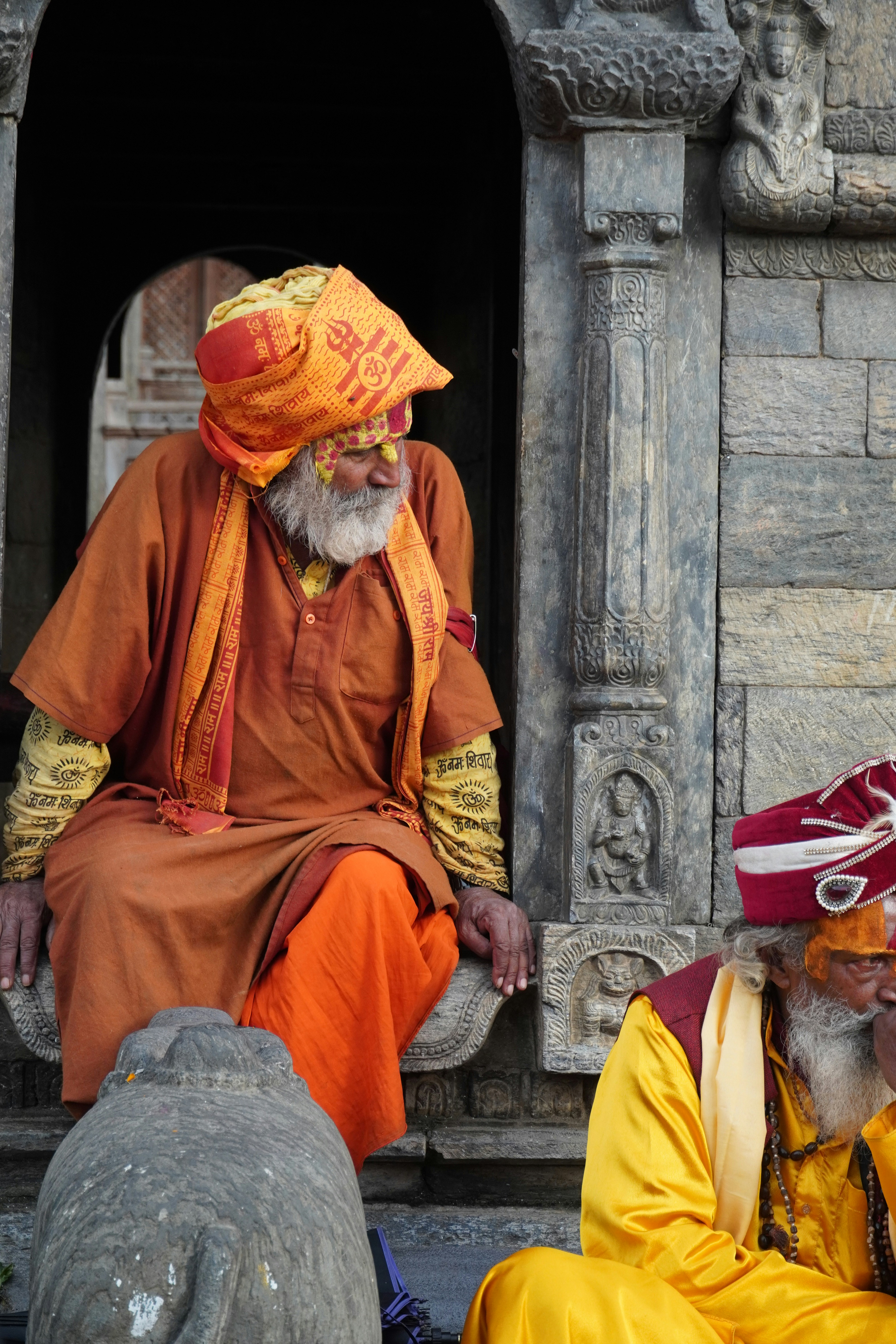 Two sadhus in traditional orange and yellow robes.