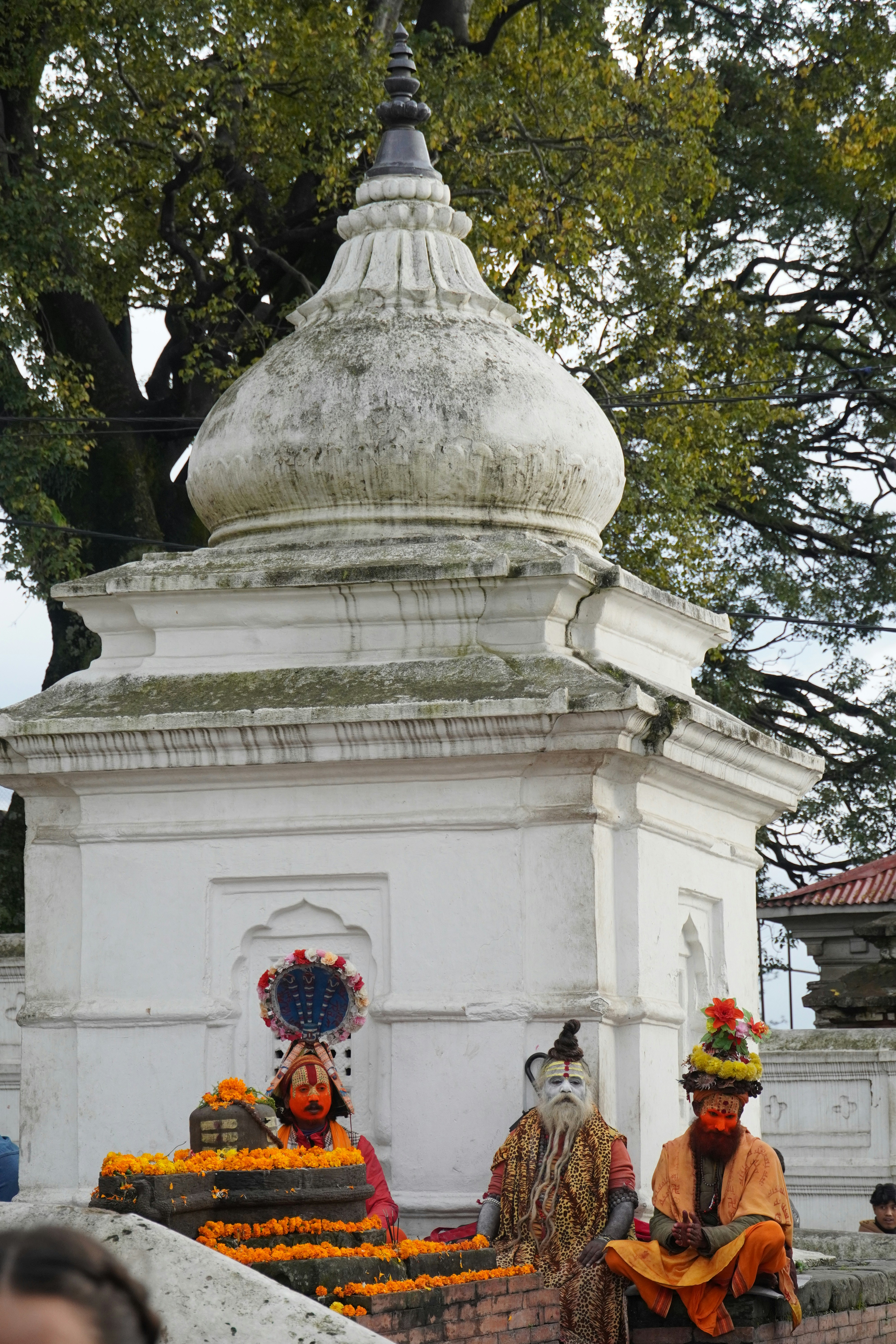 伝統的な衣装を着た二人の人物が白い構造物の近くに座っている。