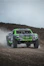 Green off-road racing truck kicking up dust