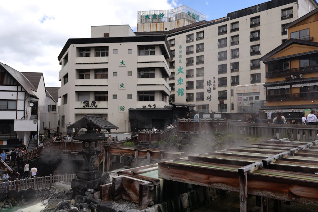 Steam rising from the wooden hot-water channels of Kusatsu Onsen with ryokan behind