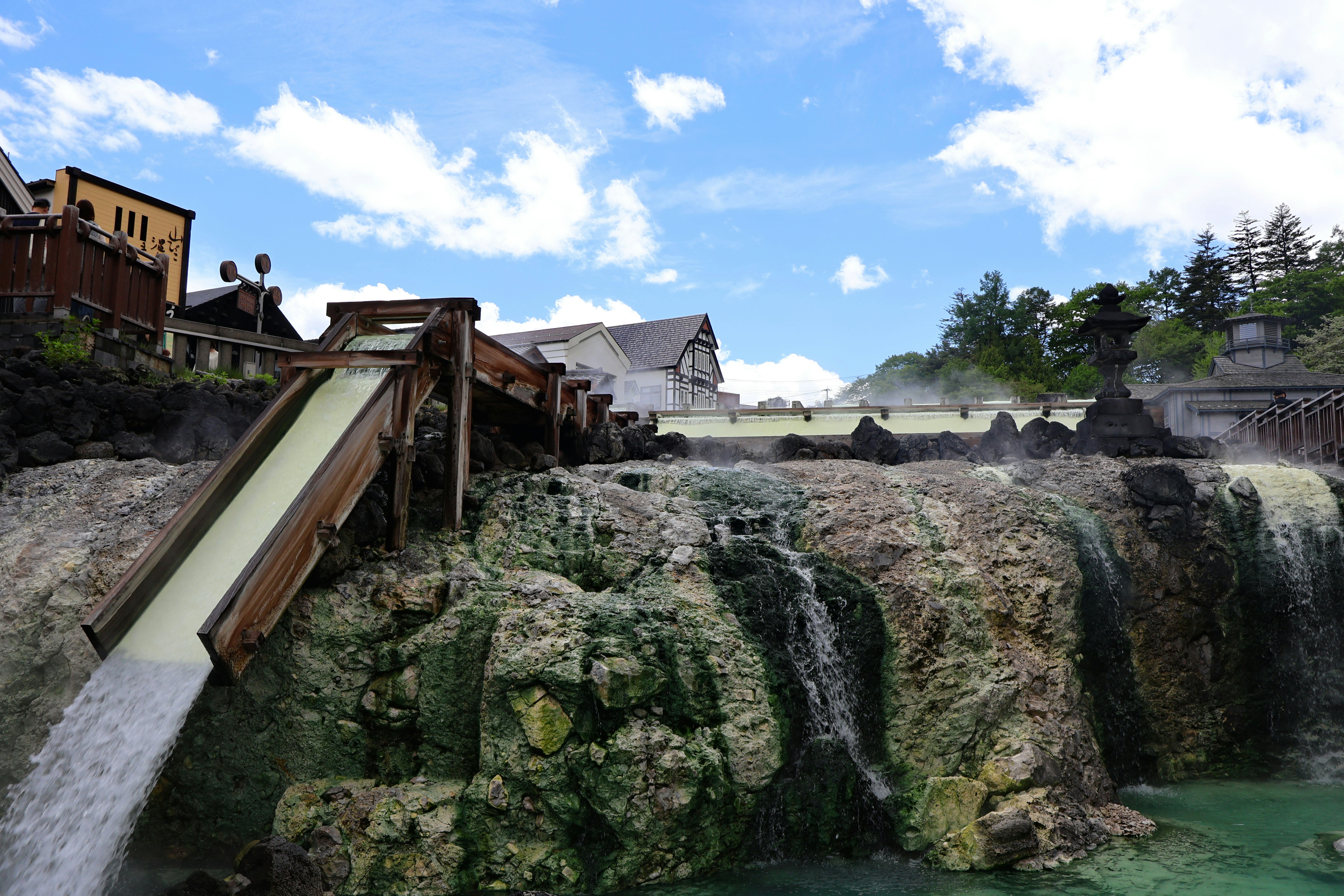 Water flows down a rocky cascade near buildings.