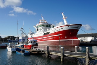 Red and white fishing boat docked at harbor
