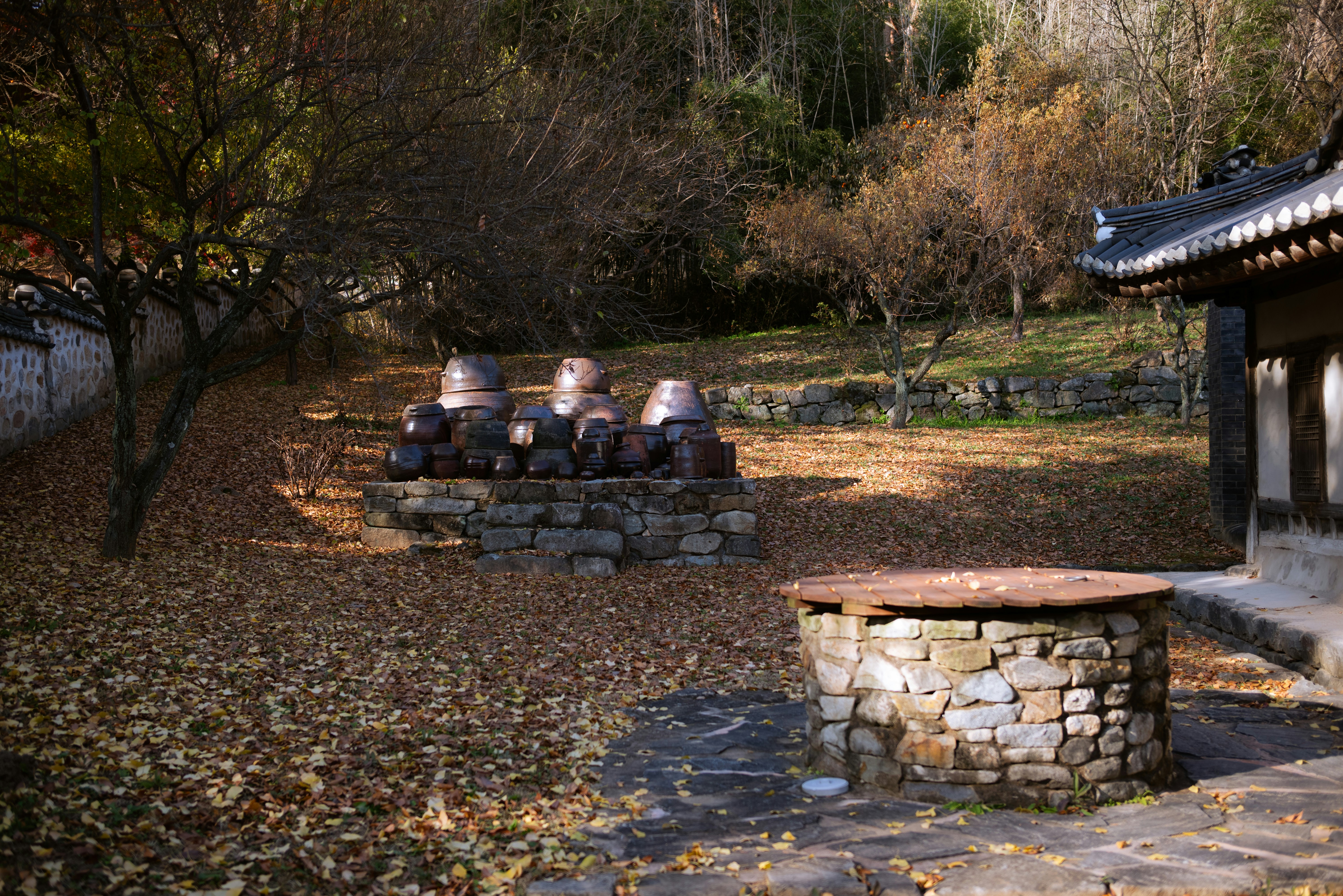 Stone well and jars in autumn courtyard