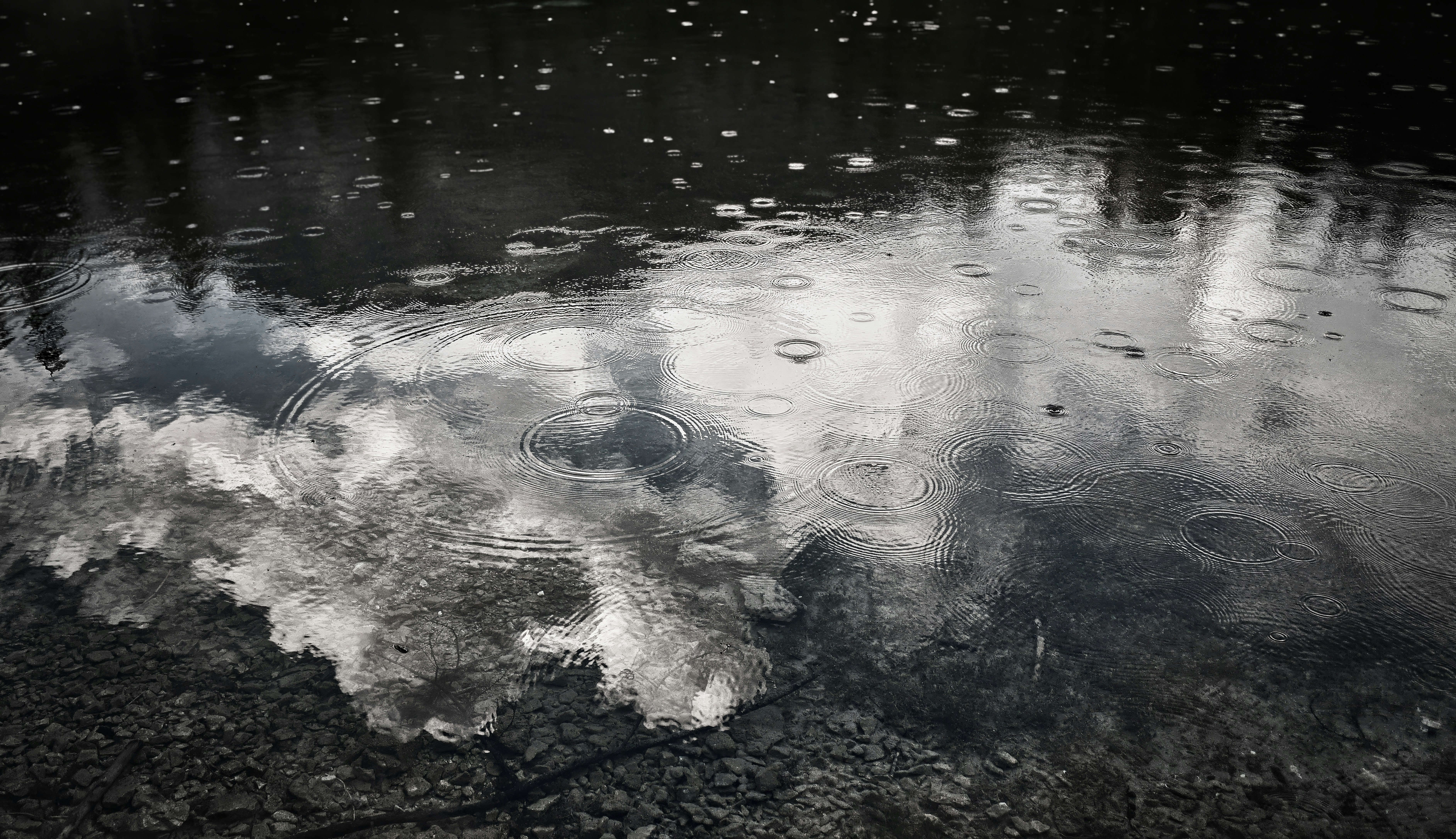 Raindrops falling on a cloudy sky reflection