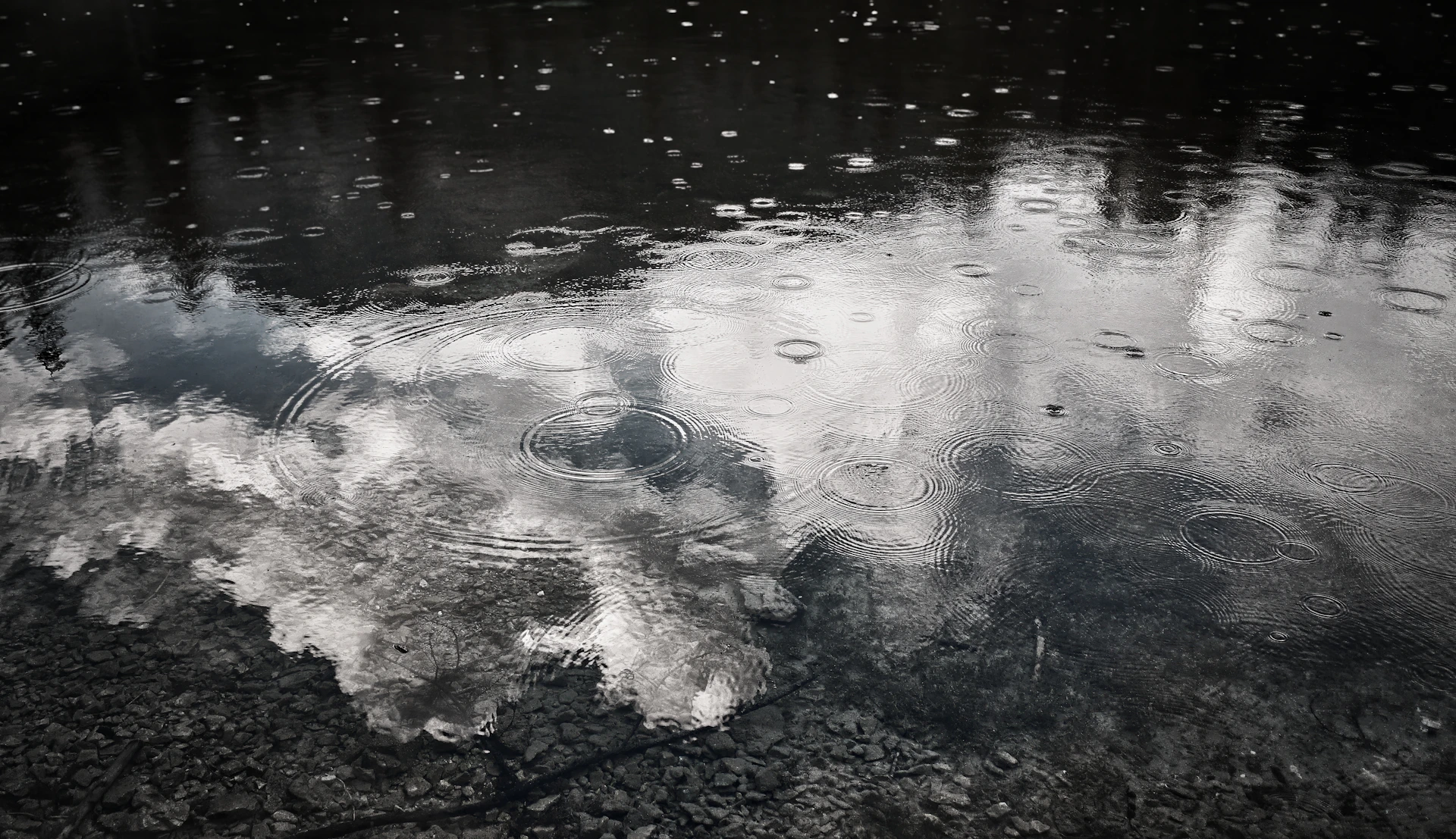 Raindrops falling on a cloudy sky reflection