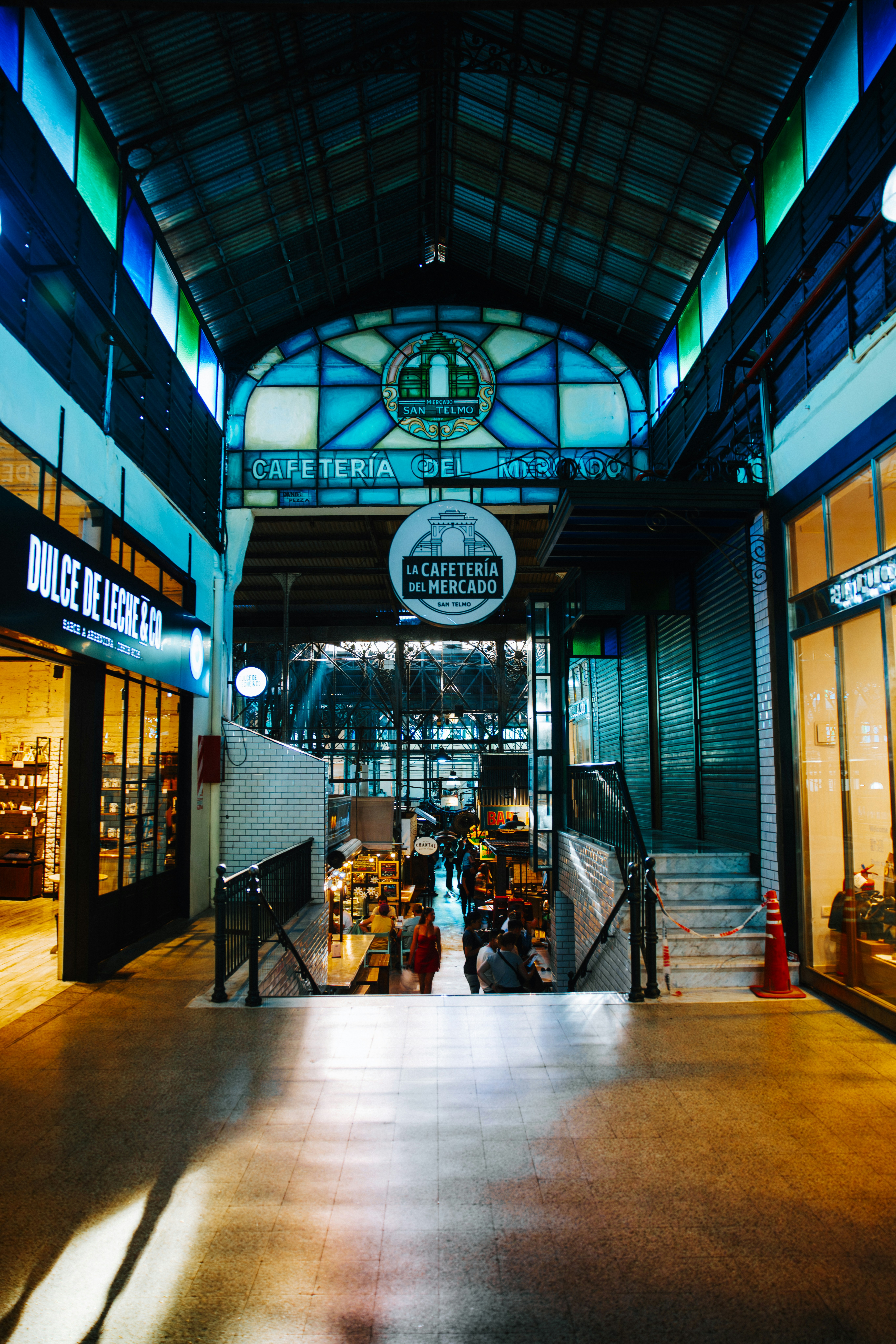 Interior of a bustling market with shops and cafes.
