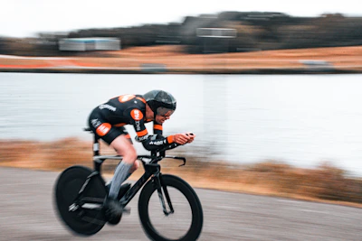 Cyclist racing by a body of water