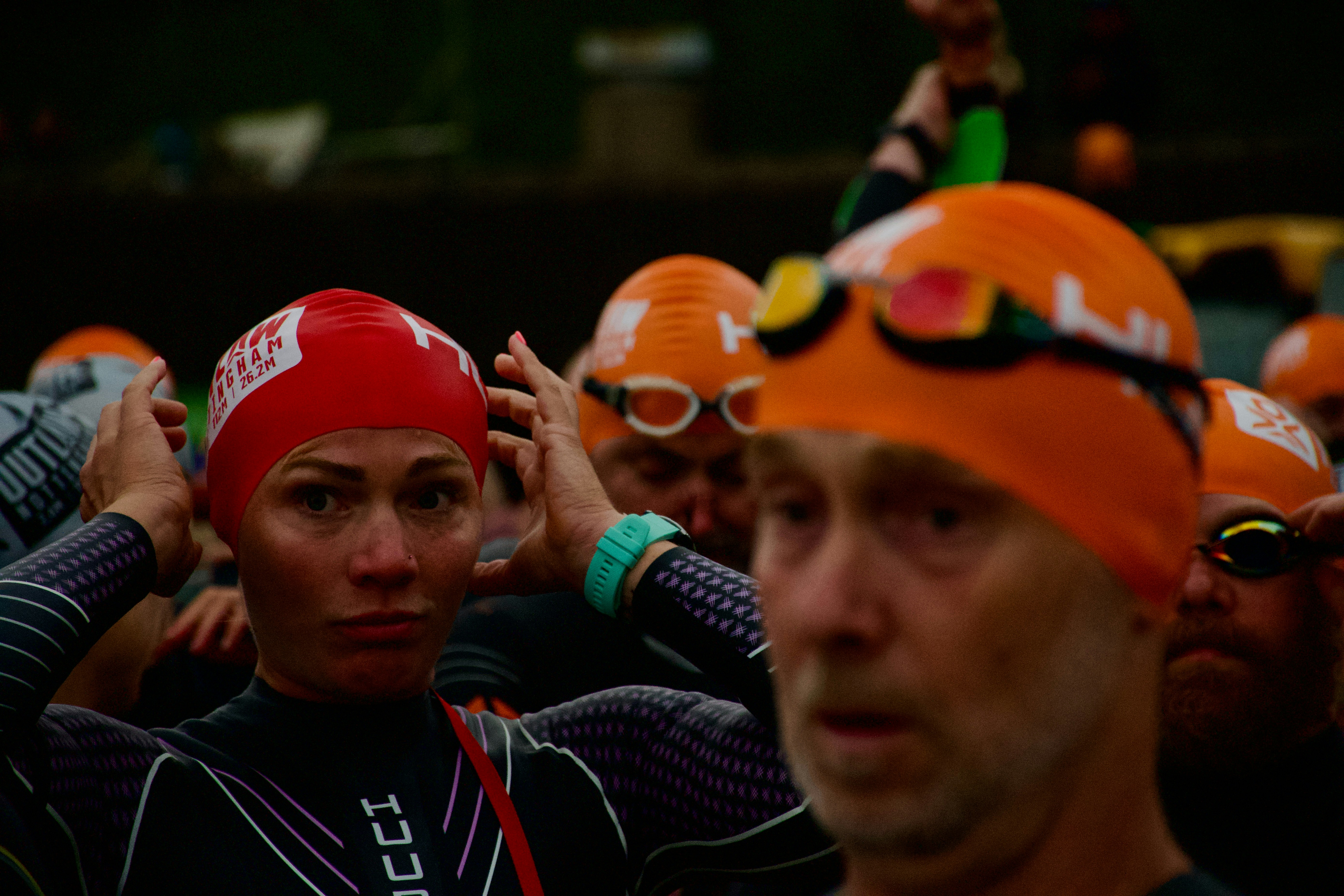 Swimmers in orange and red caps preparing for race.