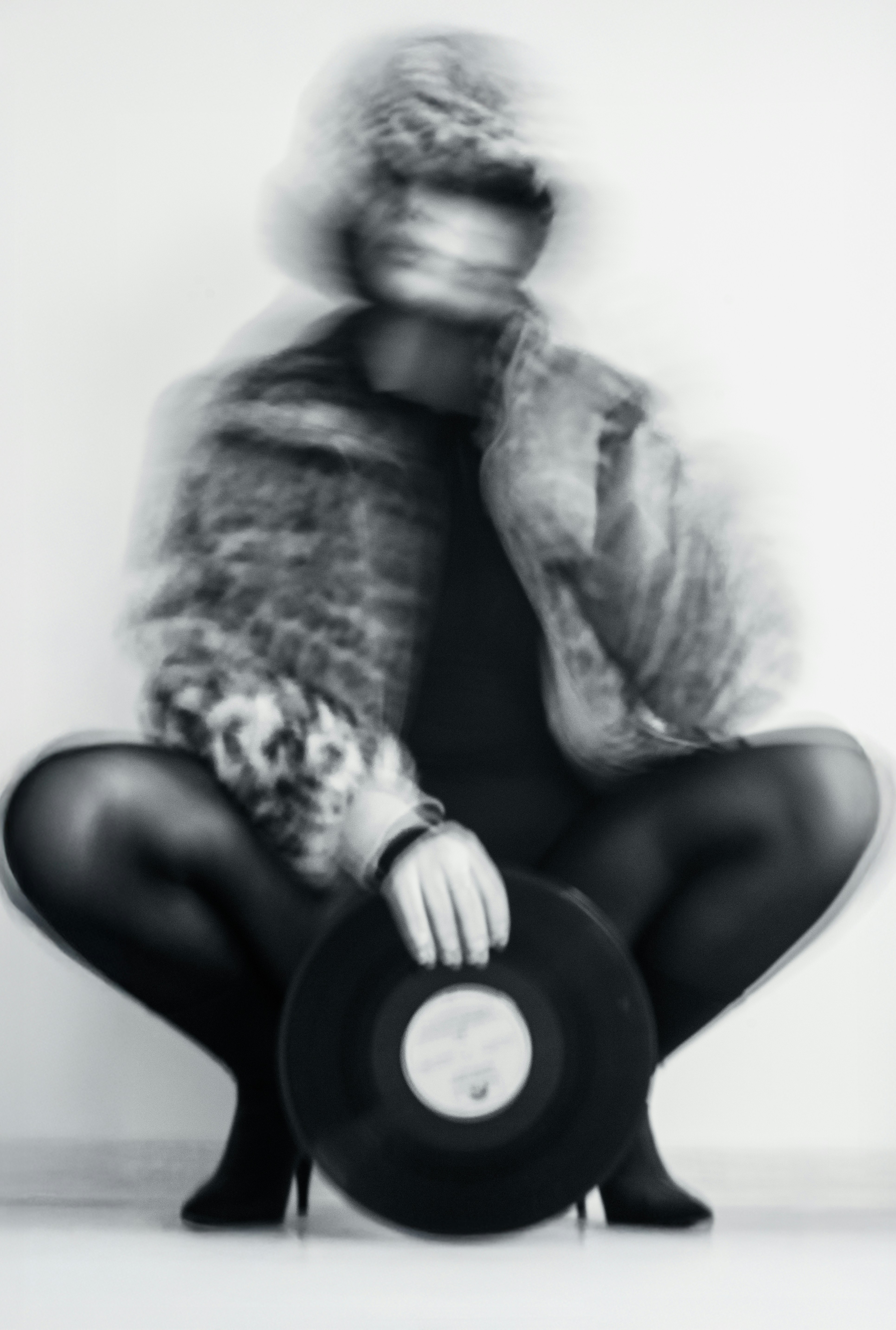 Blurry figure in fur coat holding vinyl record